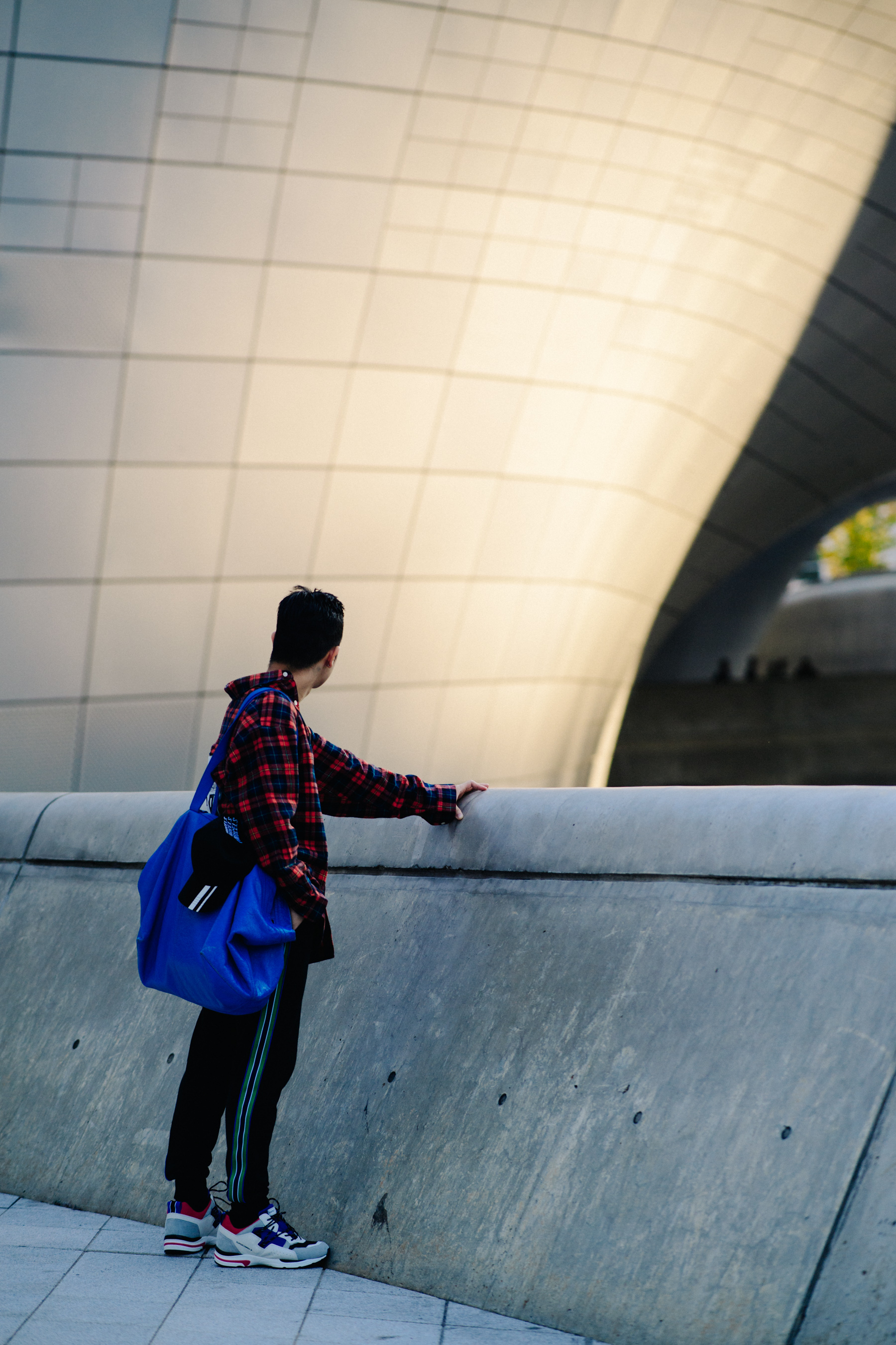 Man looking over edge of building with blue bag