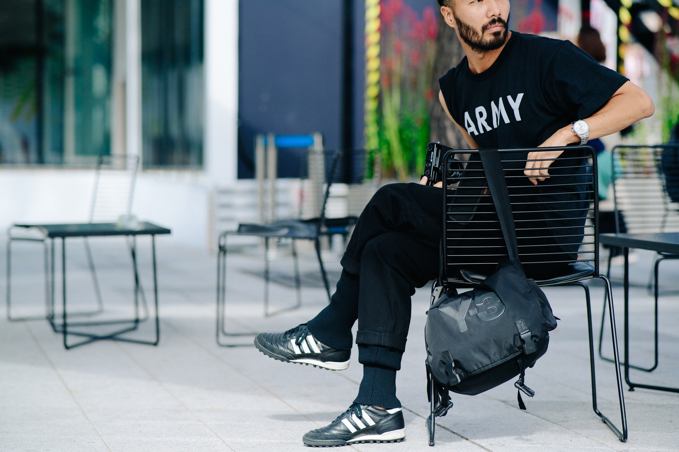 Man sitting down in black outfit with silver watch