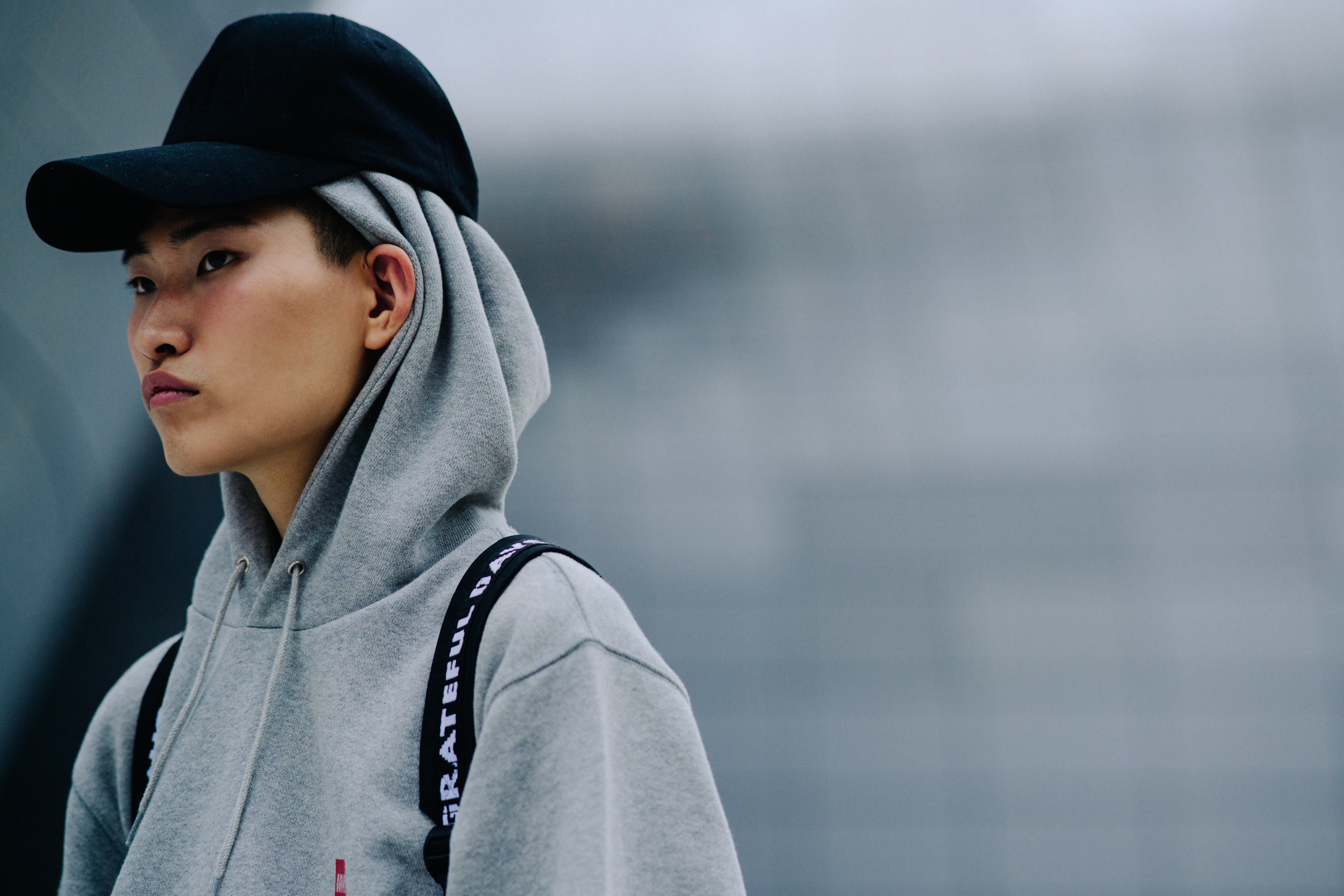 Model wearing grey hoodie under black cap