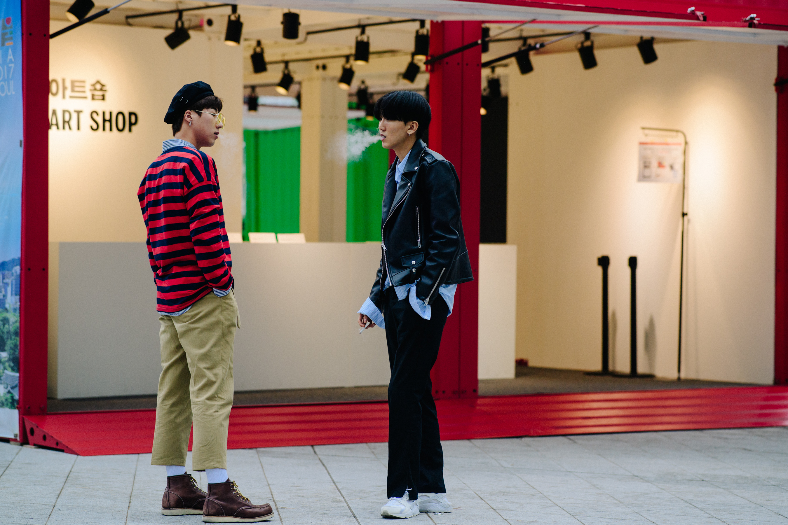Two men smoking in front of red building