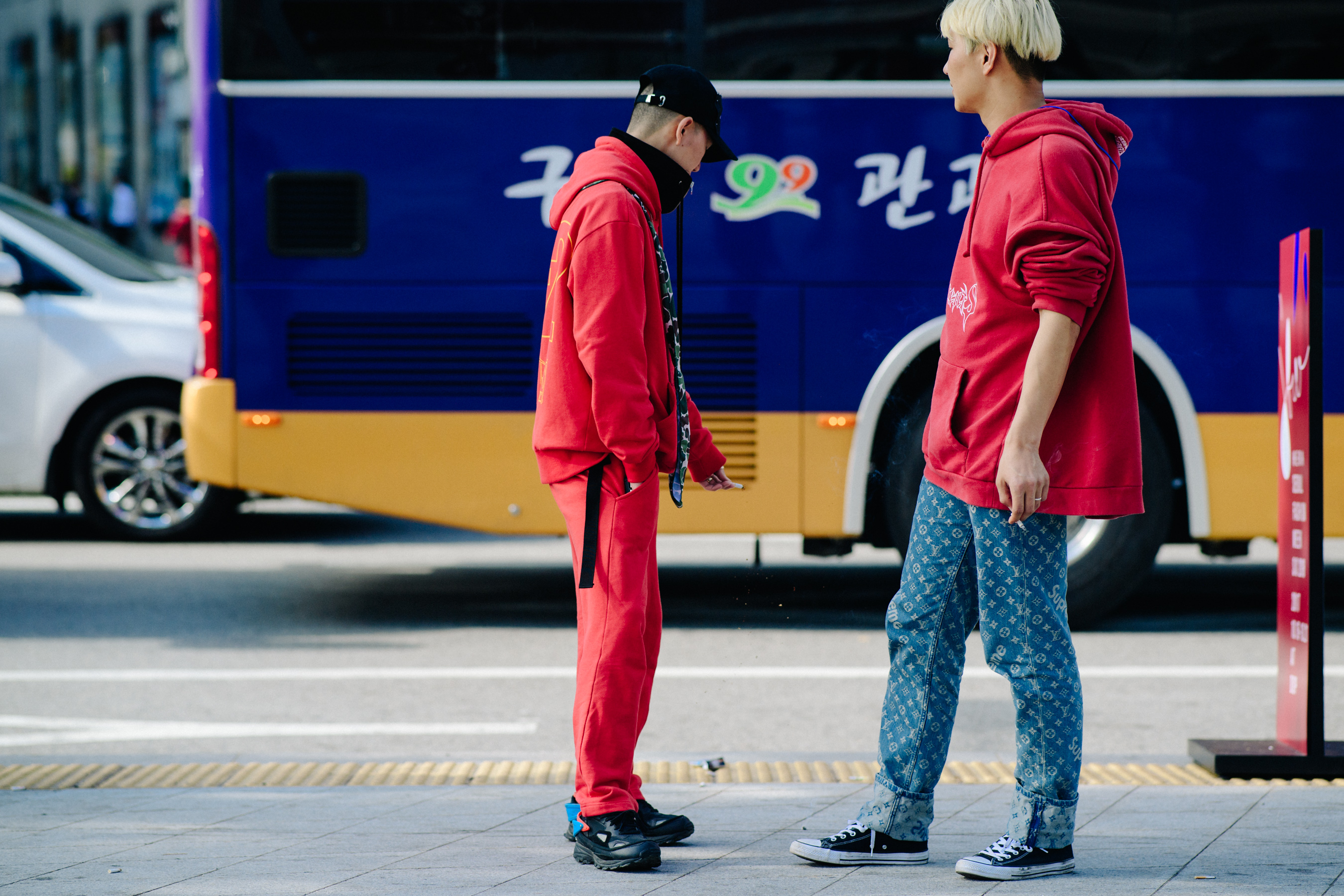 Two men smoking in red and denim outfits