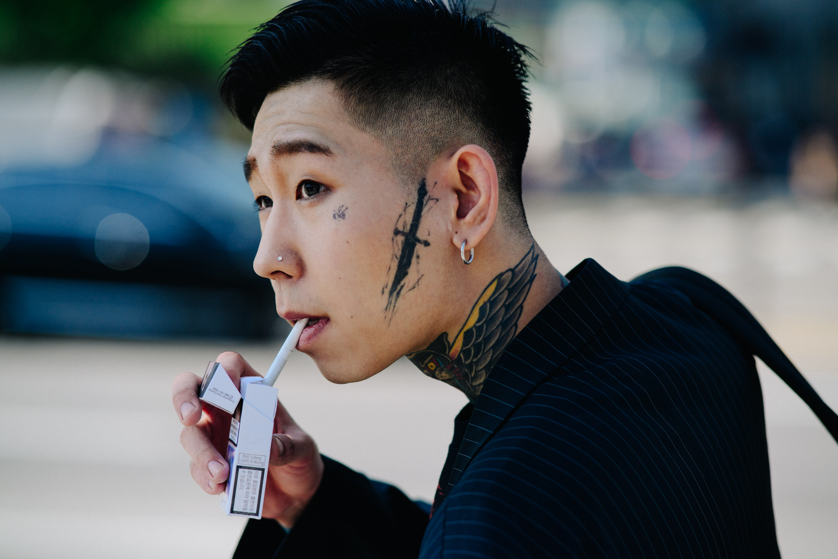 Closeup of man with face tattoos and cigarette