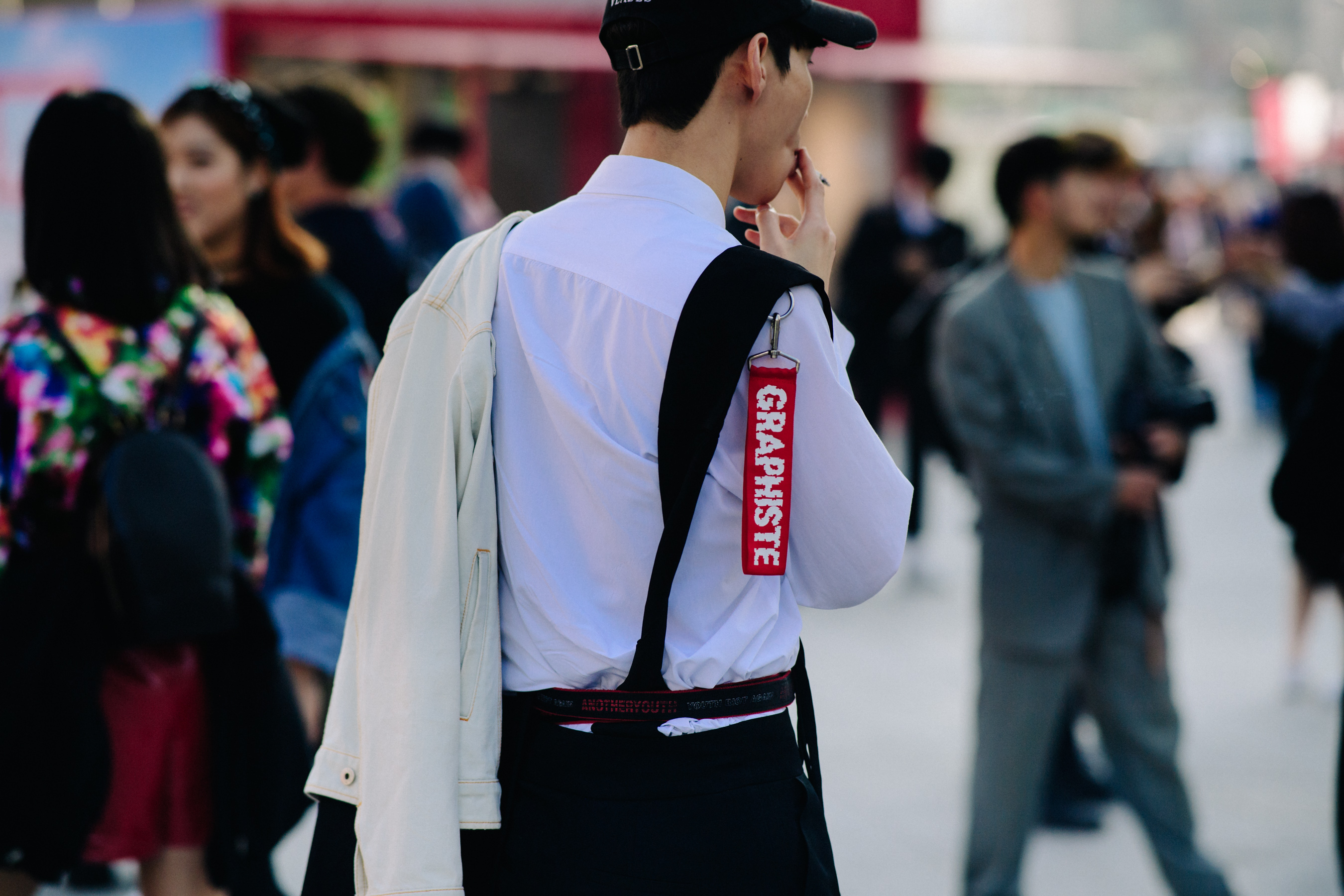 Rear of man smoking in white shirt with red tag