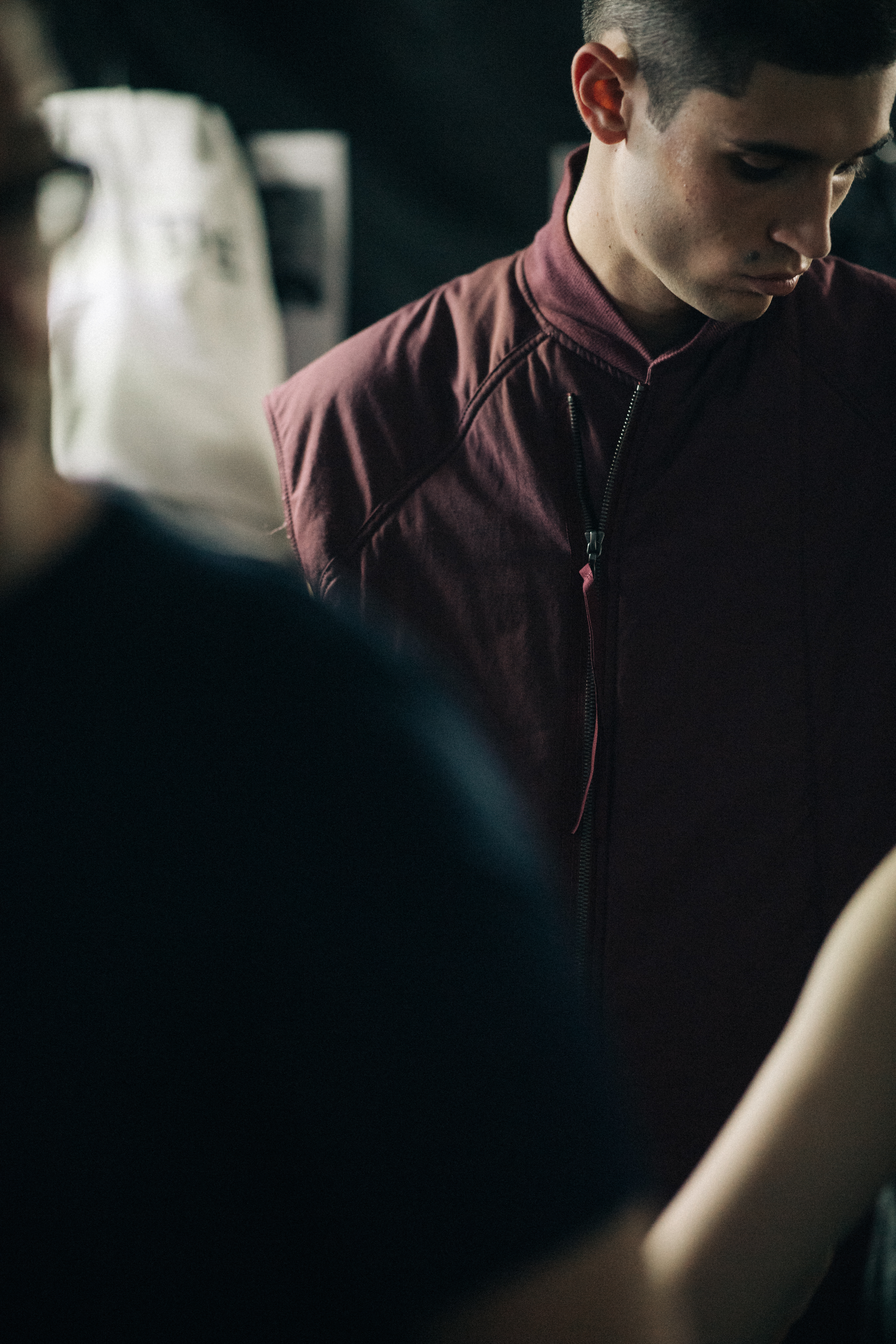 Model backstage in dark red vest