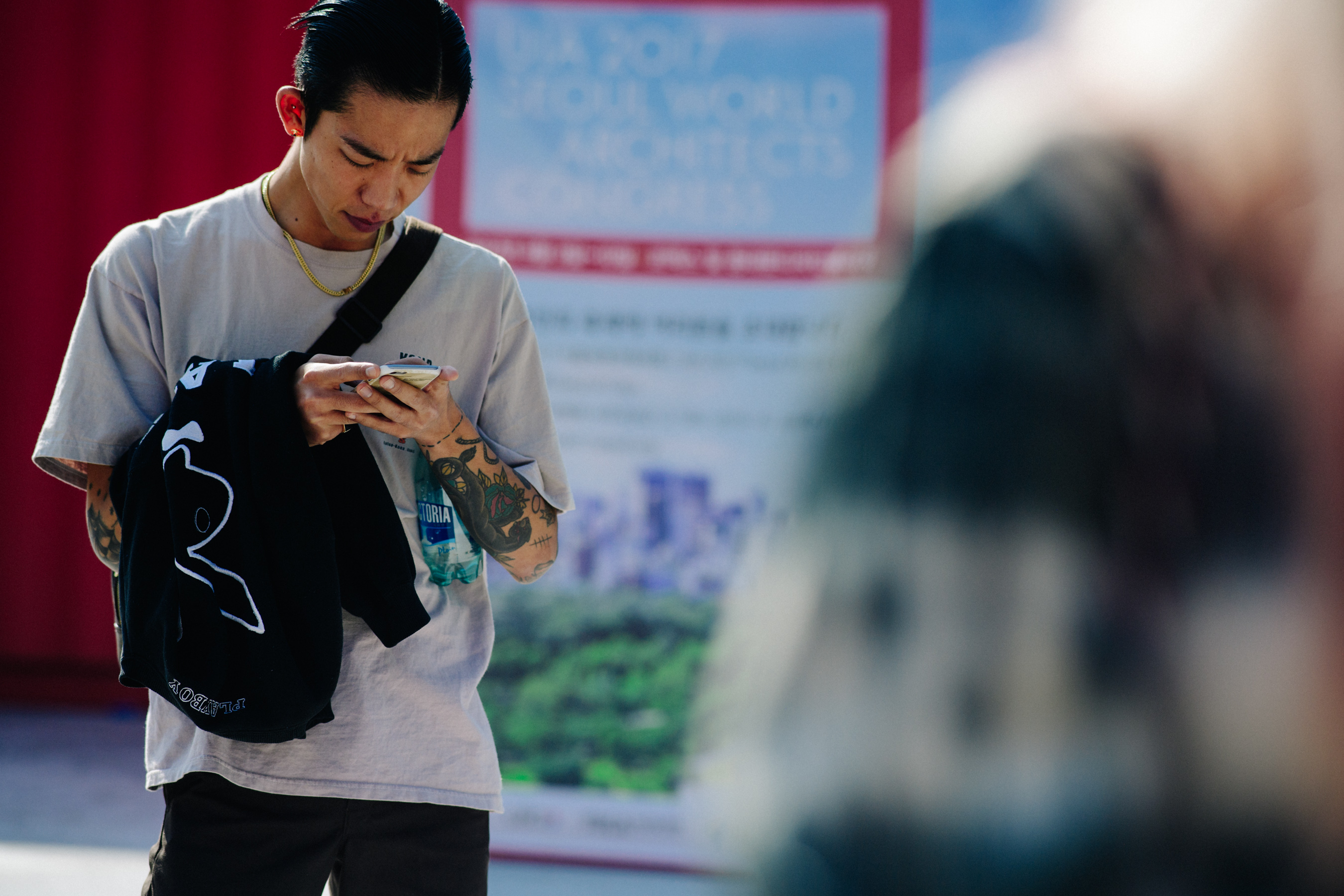 Tattooed Asian model looking at phone