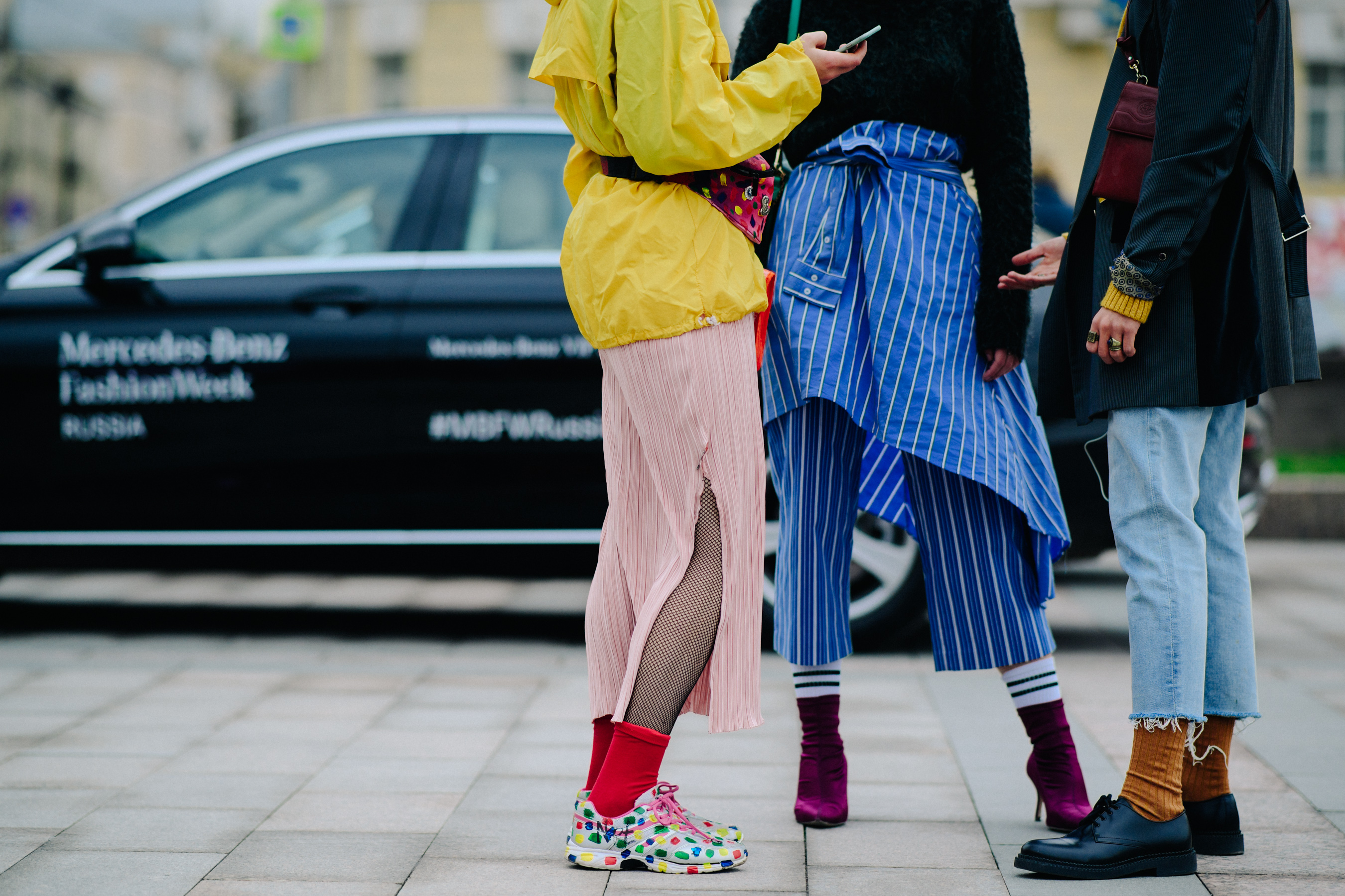Closeup of three people wearing colourful shoes and socks