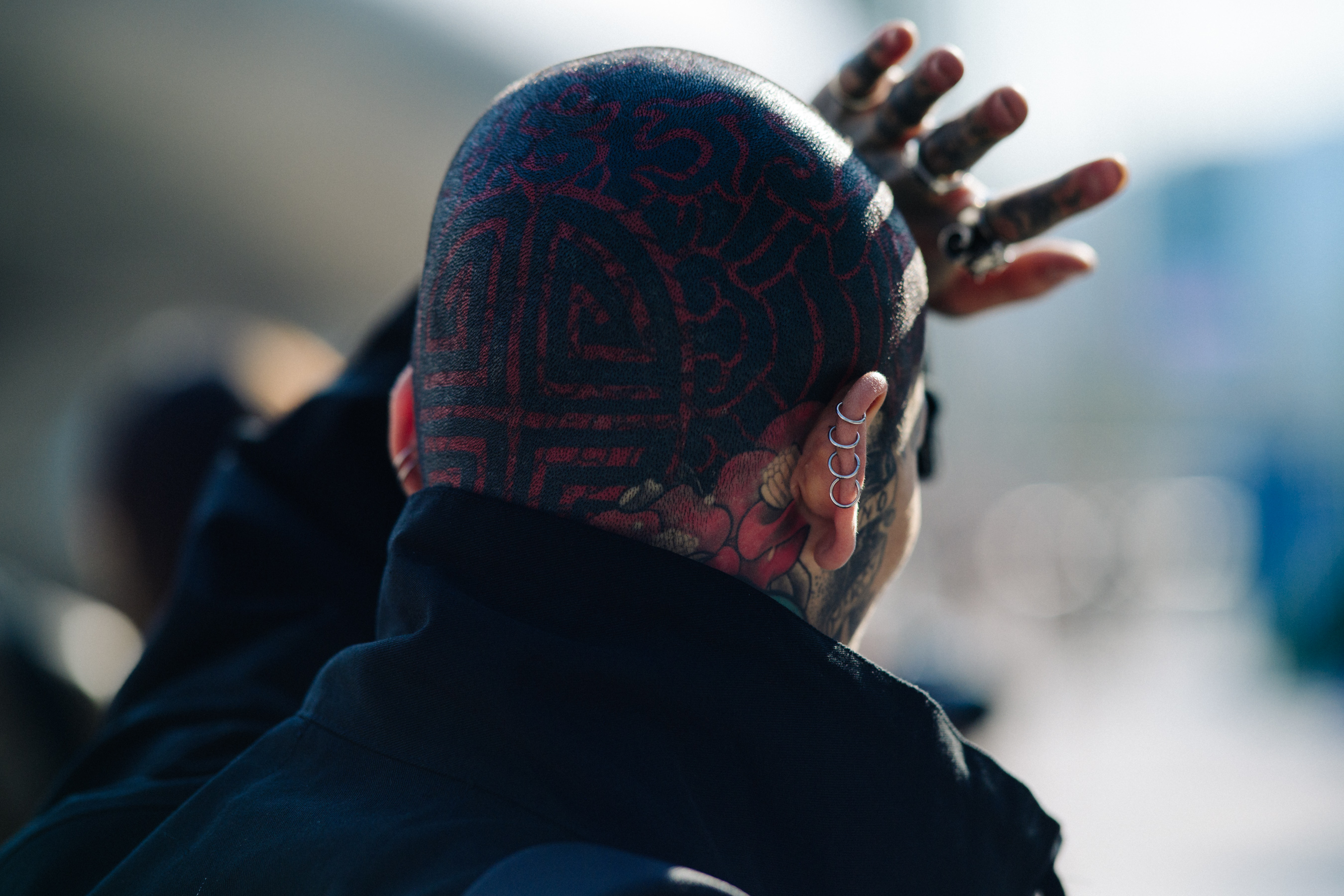 Model shielding face from sun with head tattoos