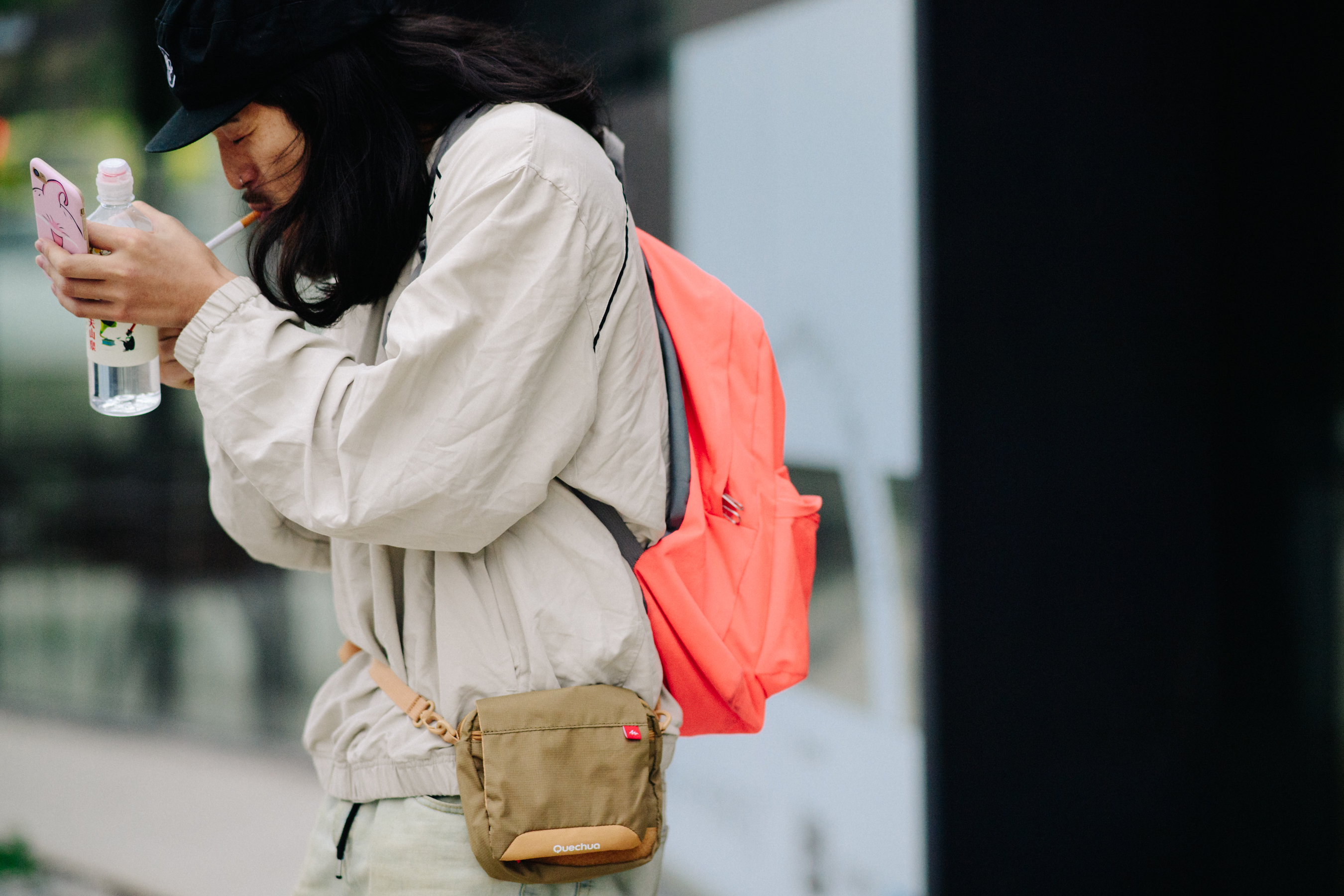 Man lighting cigarette wearing orange backpack