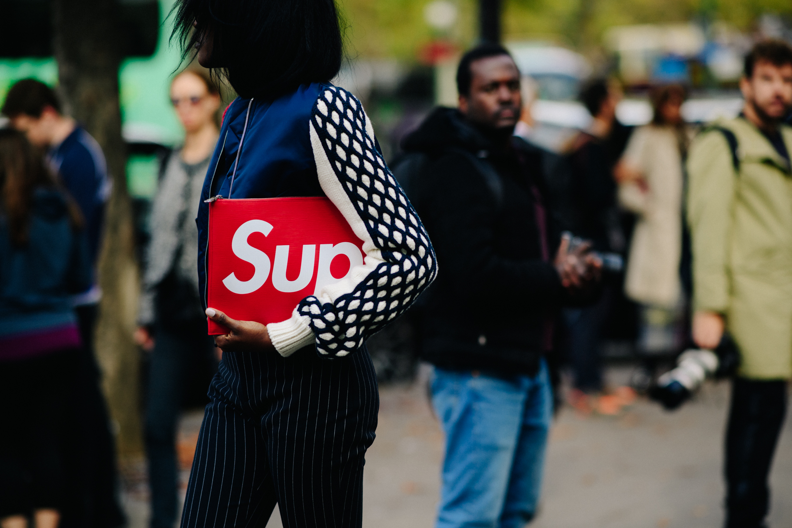 Woman holding Louis Vuitton x Supreme clutch bag