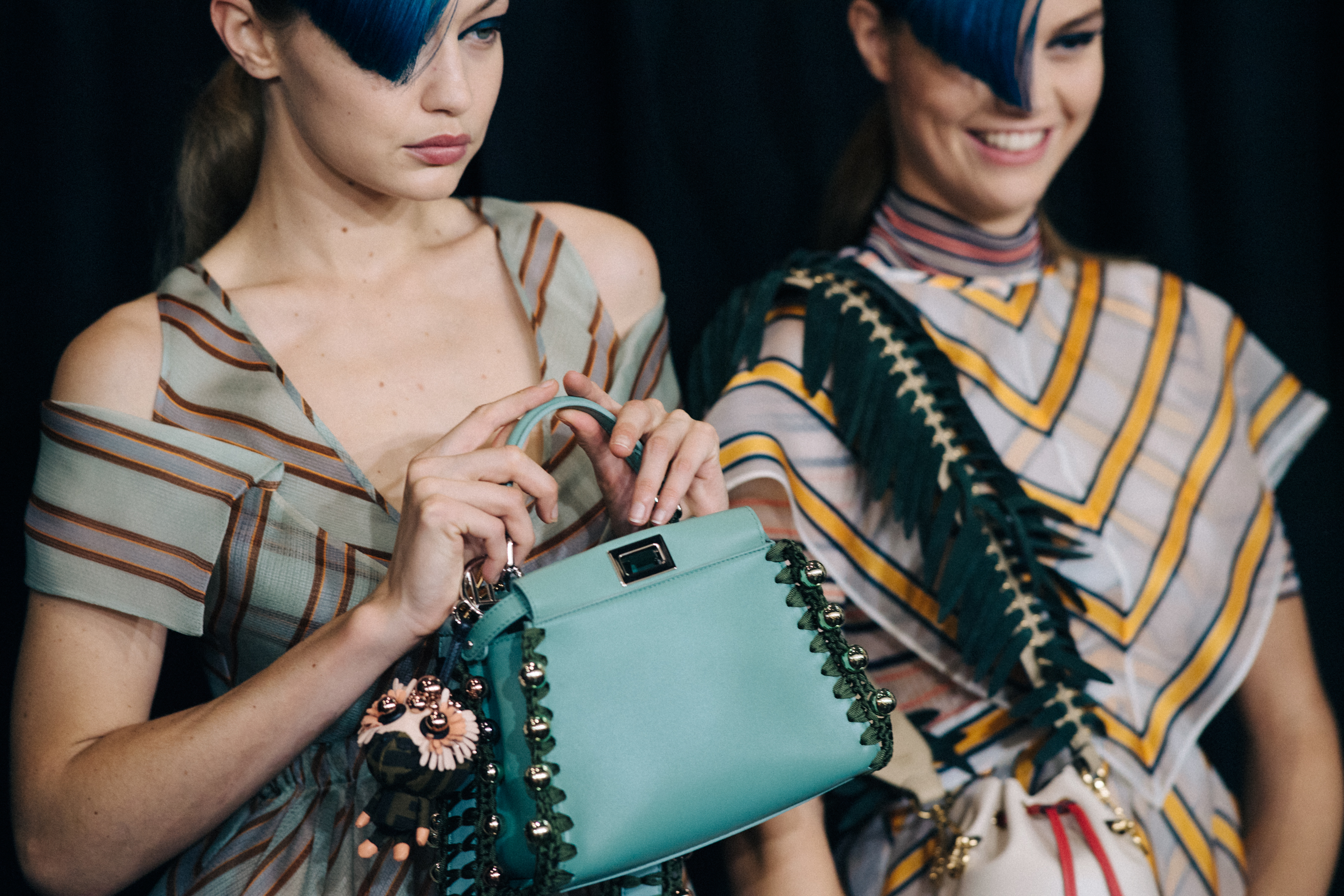 Models backstage with blue handbag