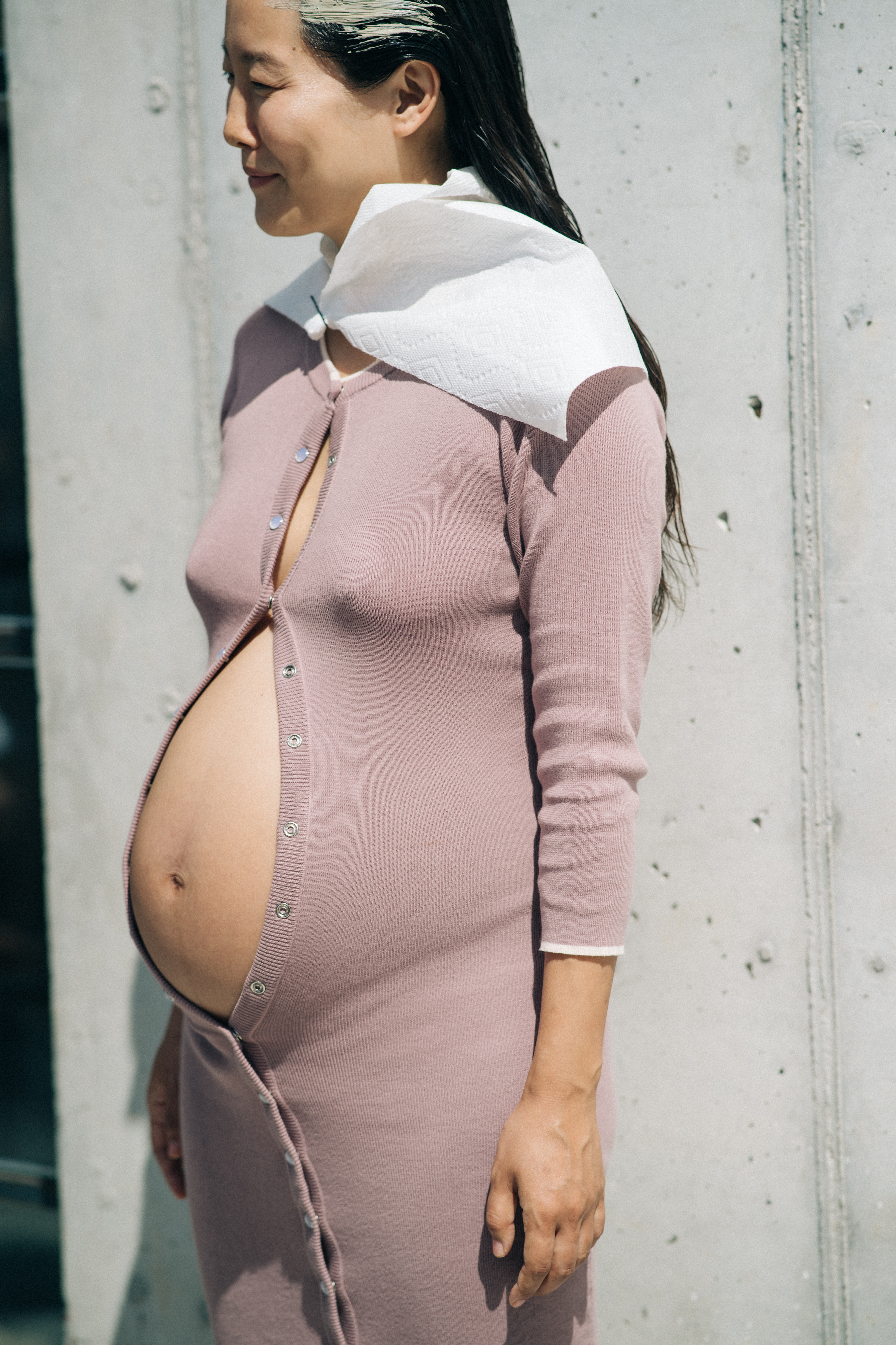 Pregnant model wearing cardigan revealing stomach