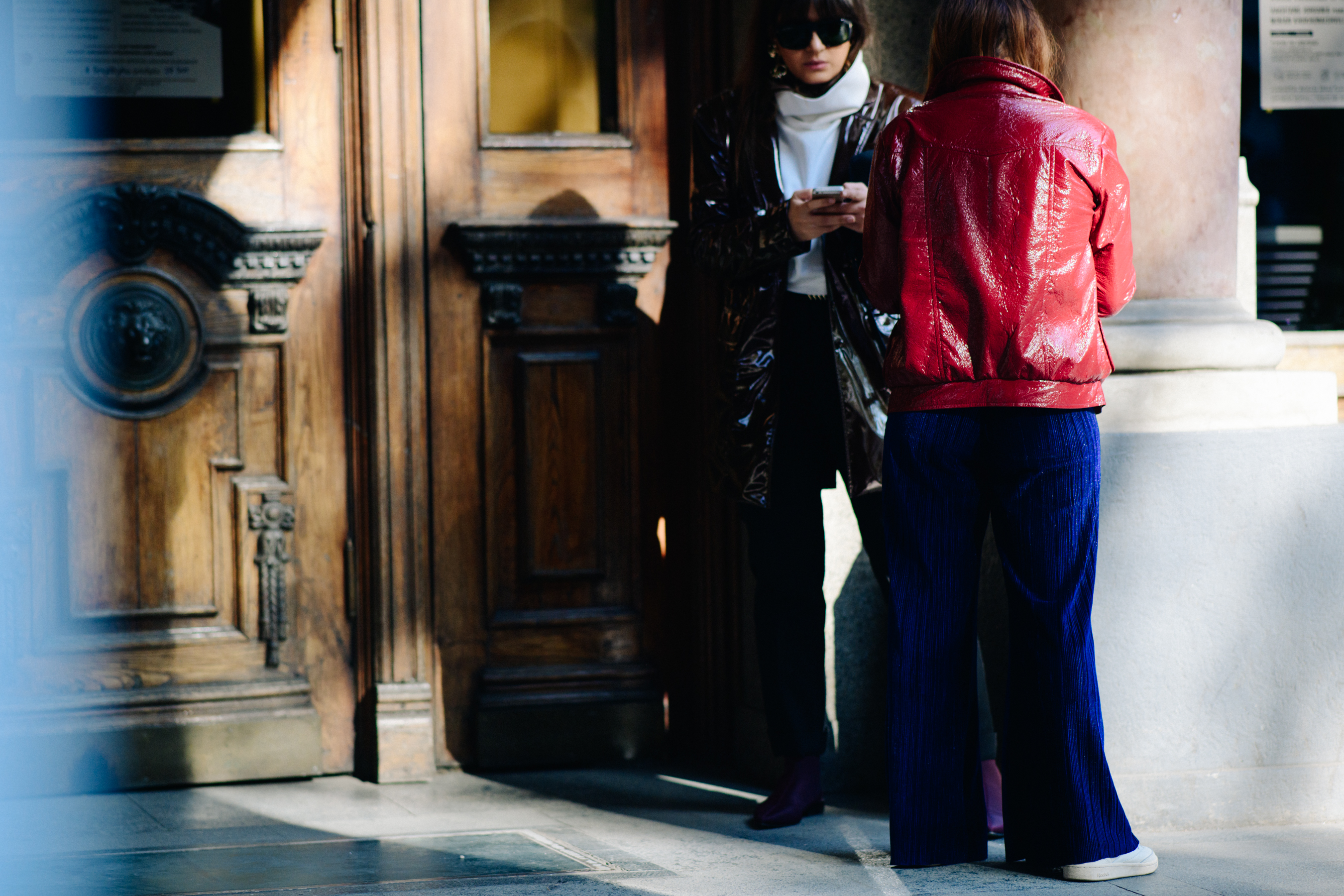 Two women wearing patent jackets