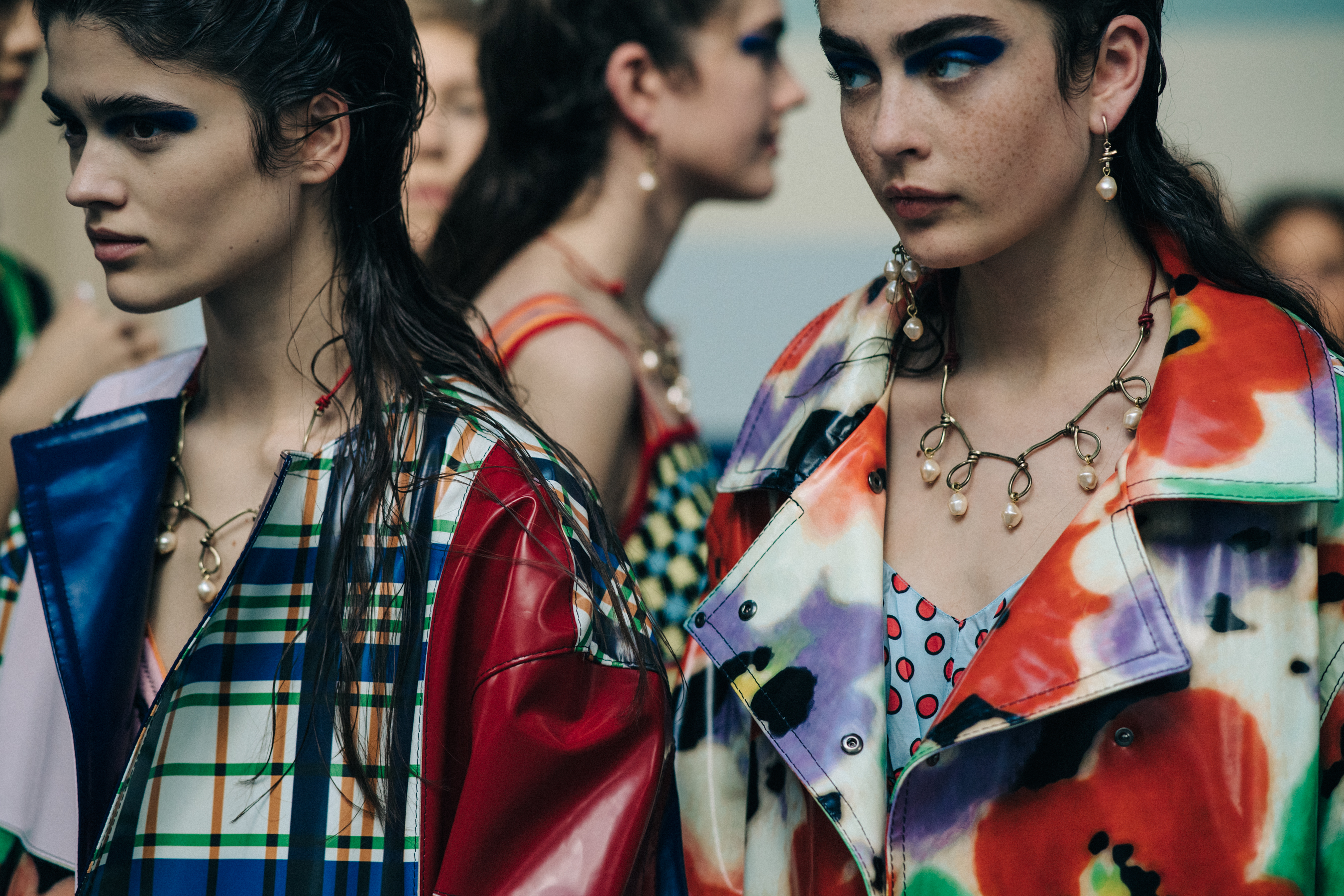 Two models backstage wearing colourful coats