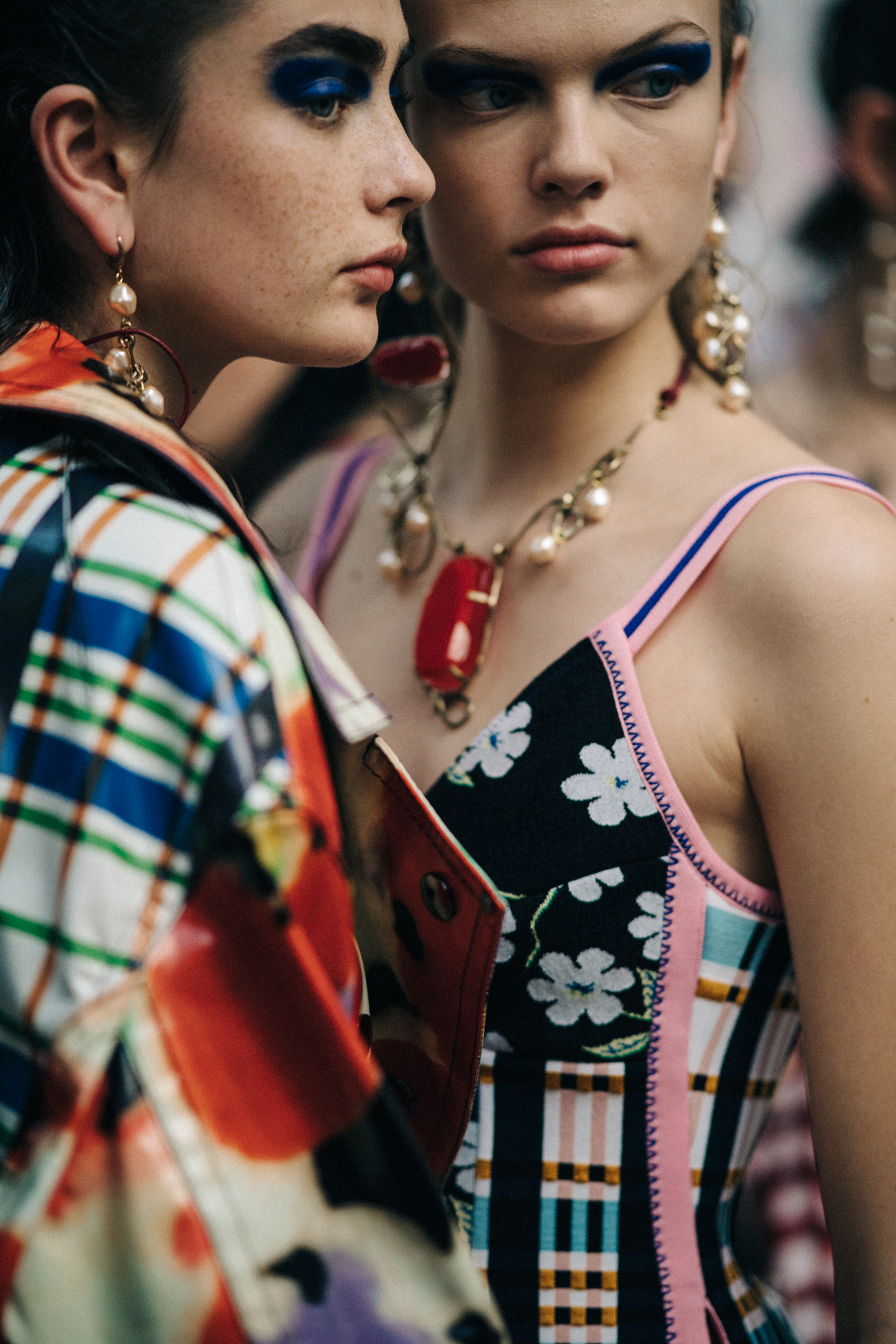 Two models backstage wearing colourful outfits