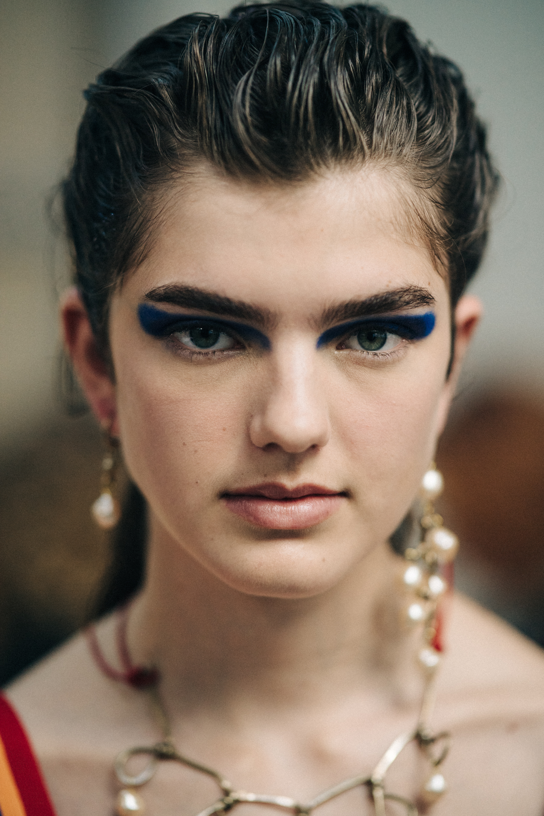 Portrait of model backstage with blue eye makeup and green eyes