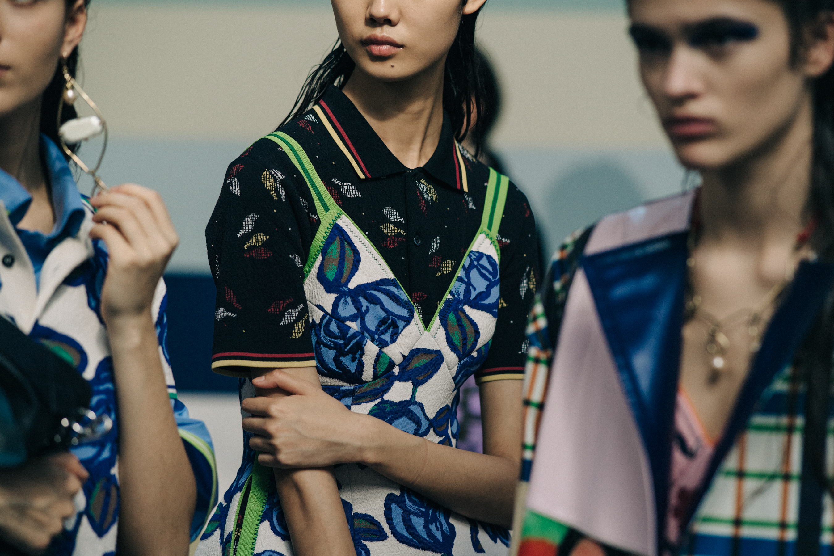 Three models backstage in colourful tops