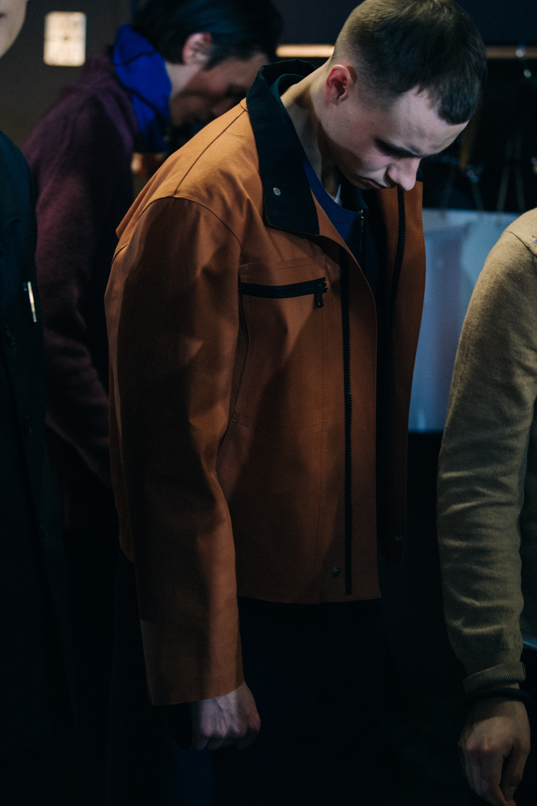 Model wearing orange jacket backstage