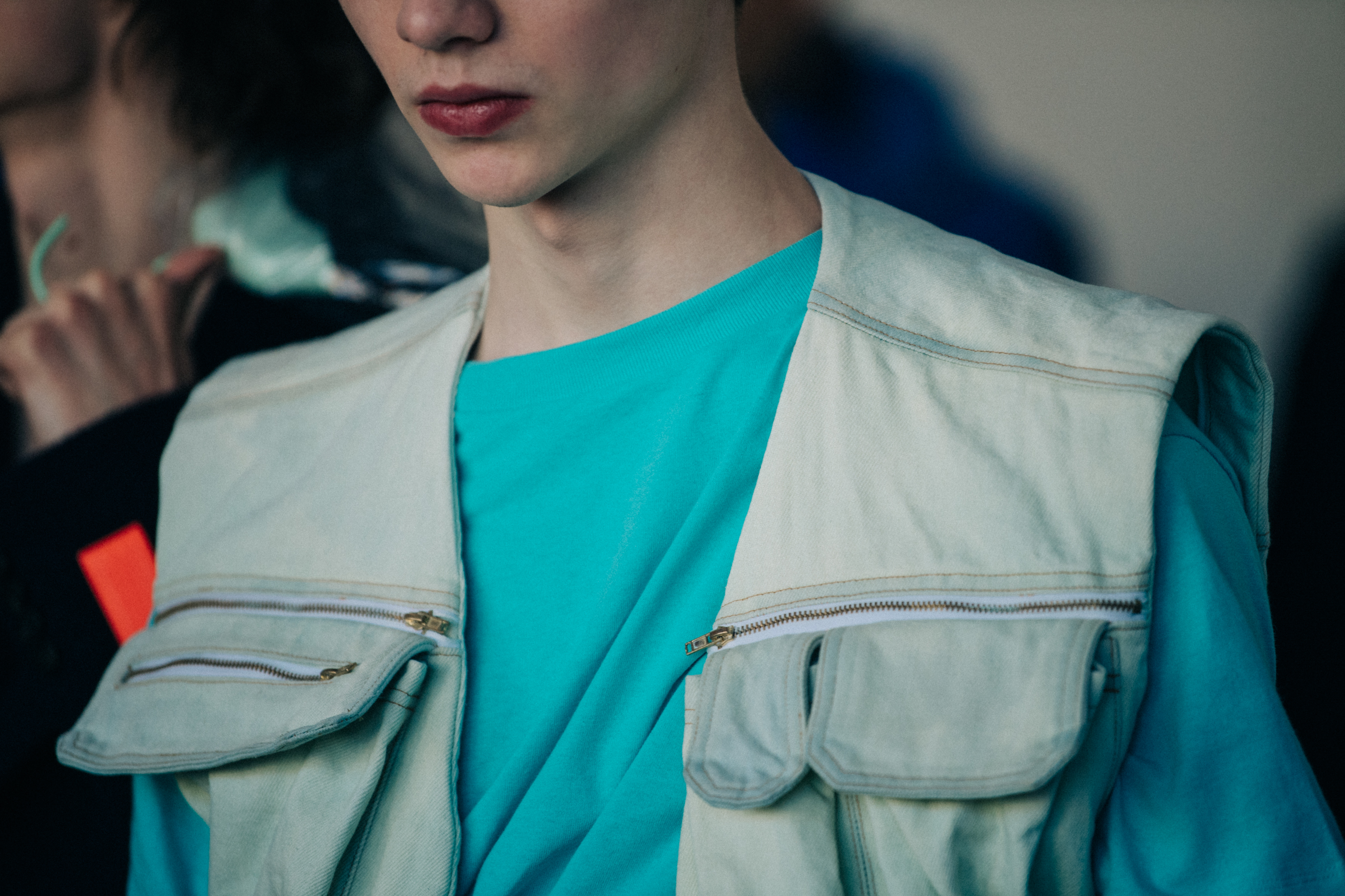 Model wearing blue shirt and white vest