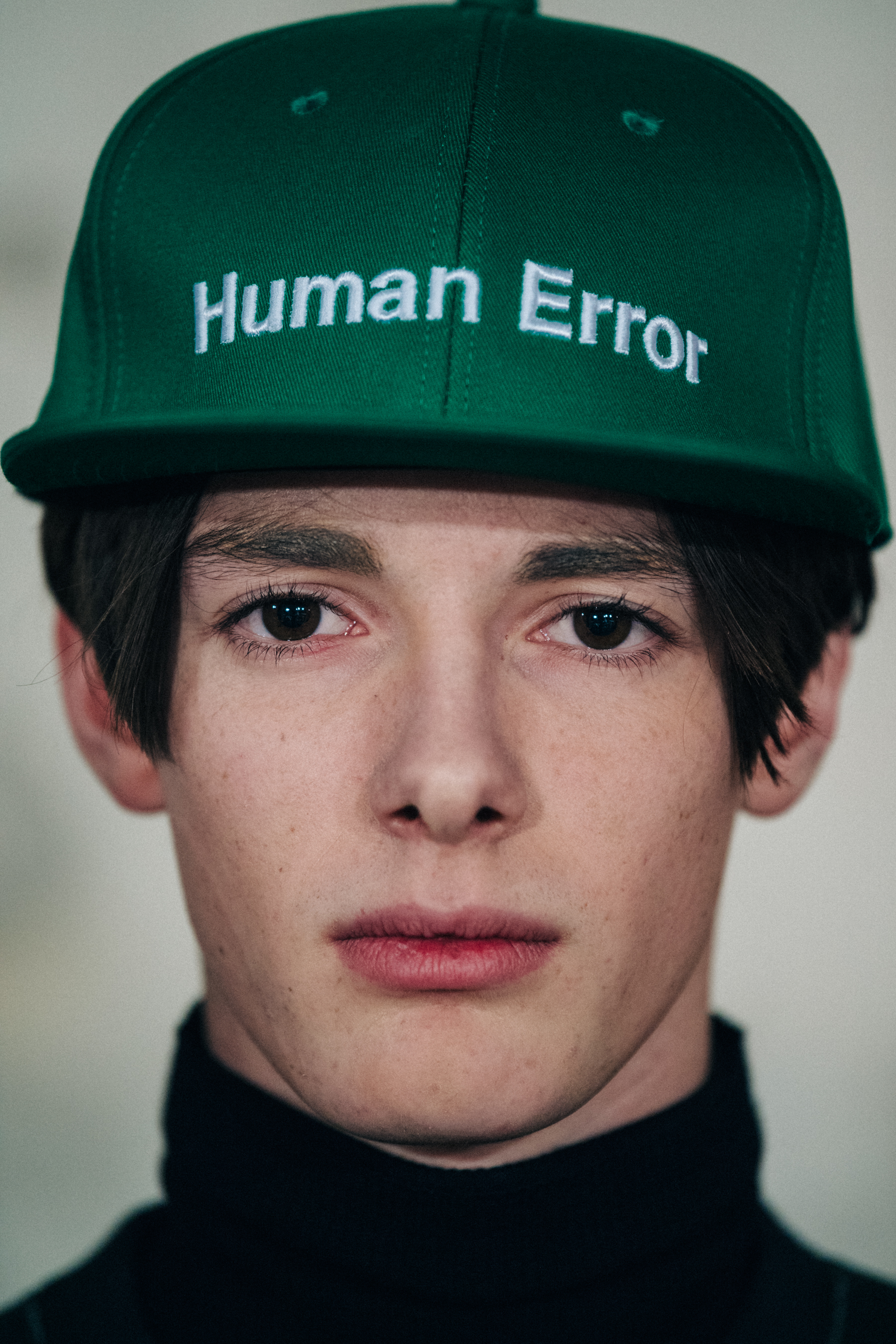 Portrait of model wearing green cap with text