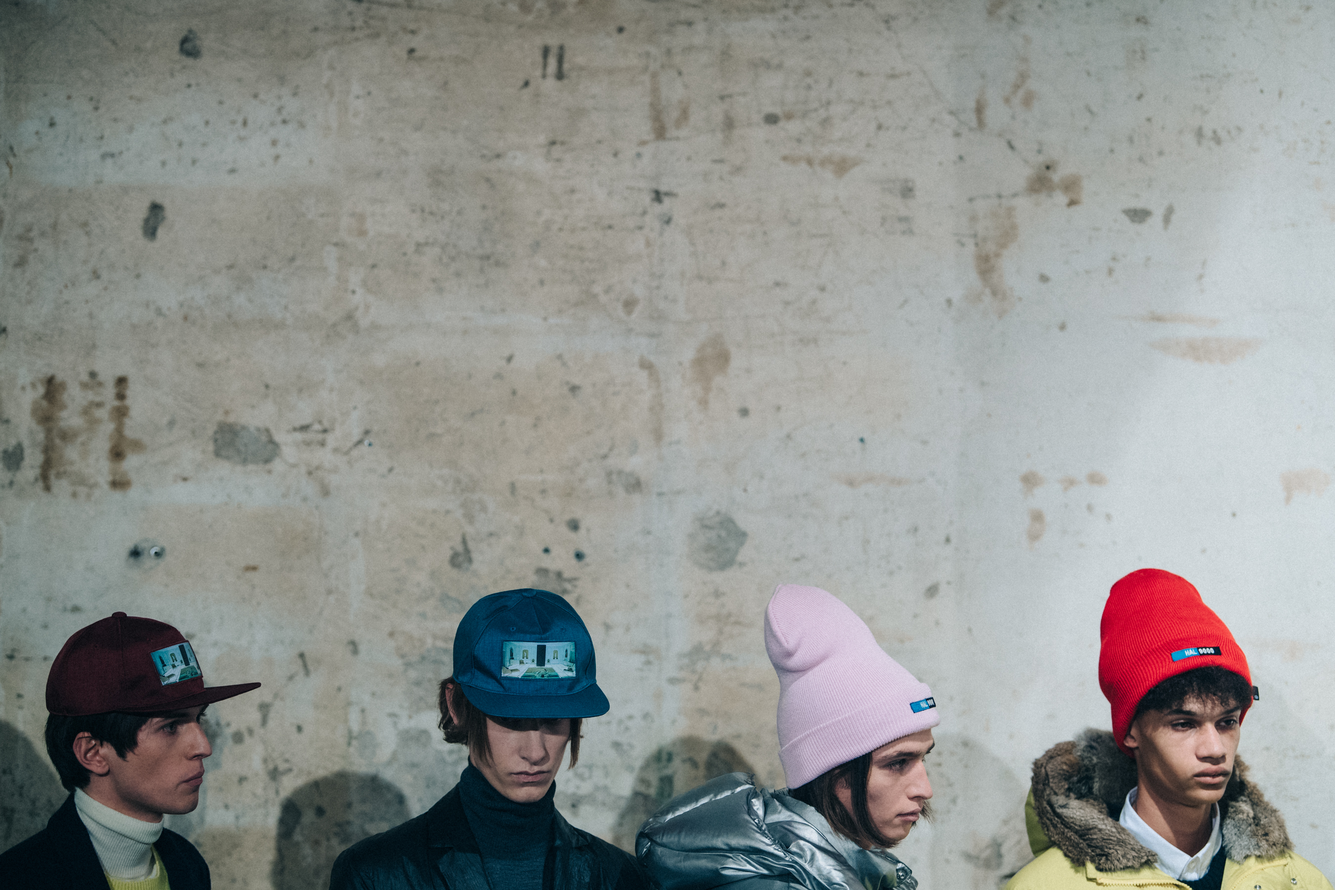 Four models wearing colourful hats backstage