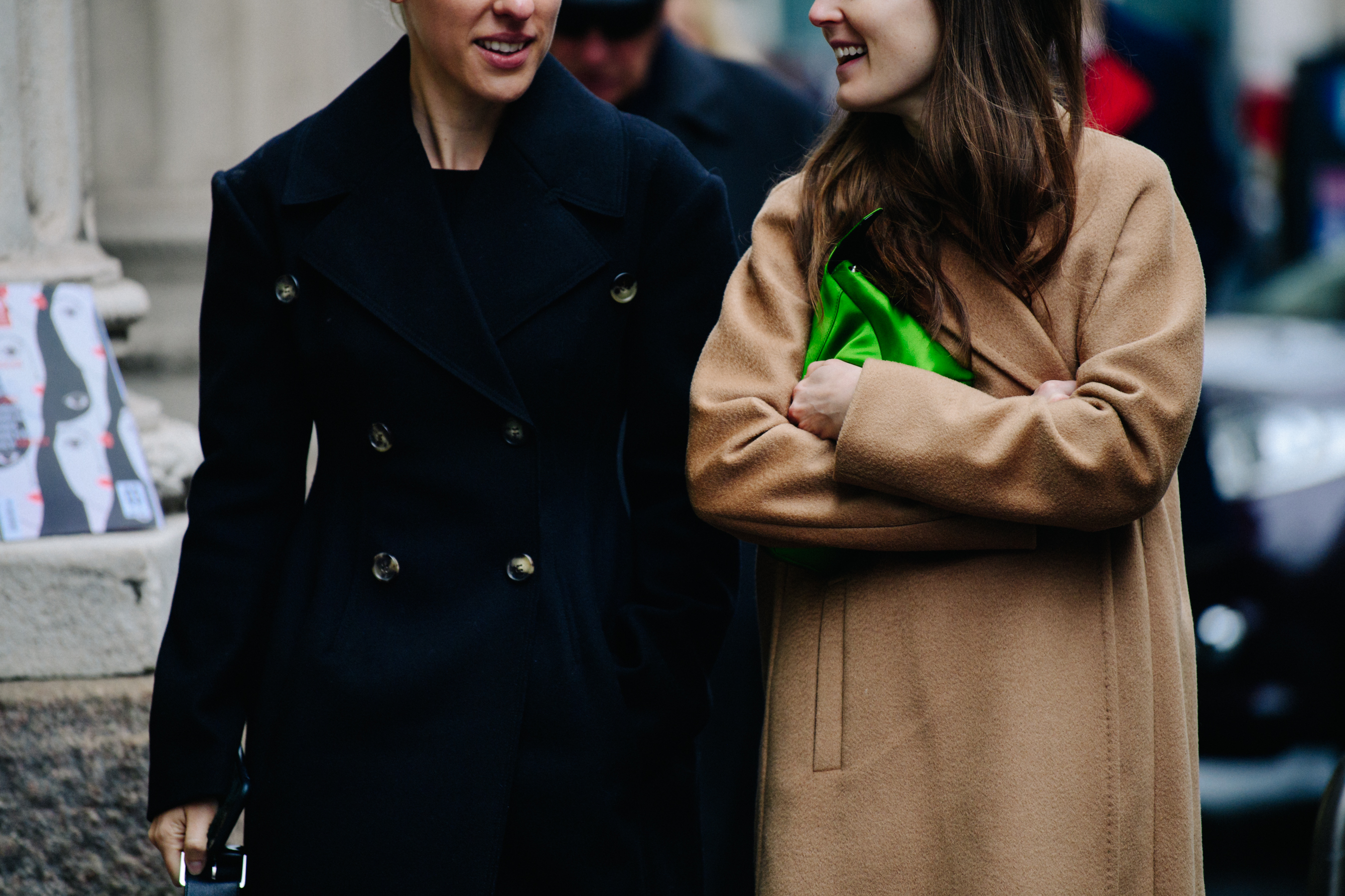 Two women wearing dark and light wool coats