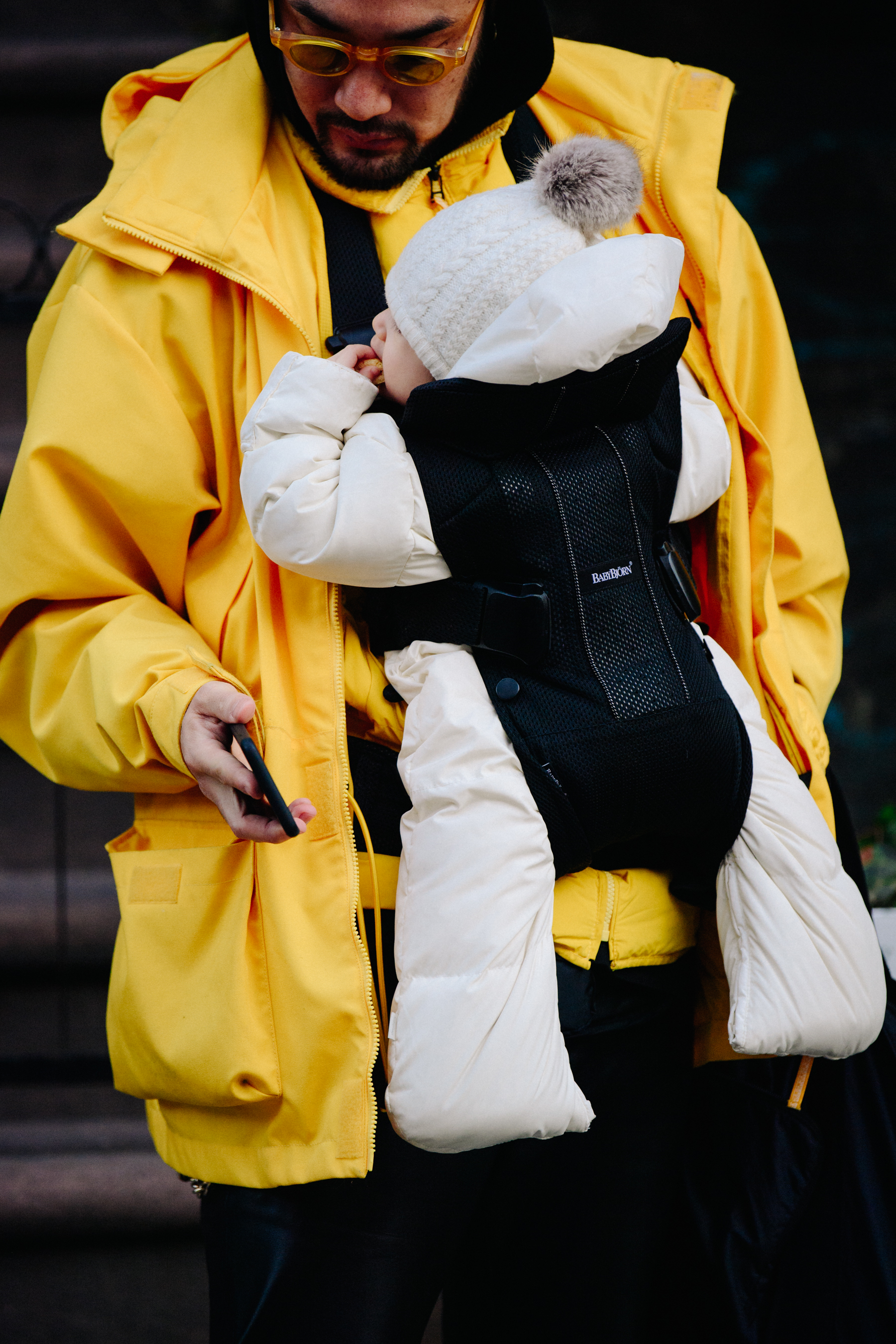 Man wearing yellow coat holding baby