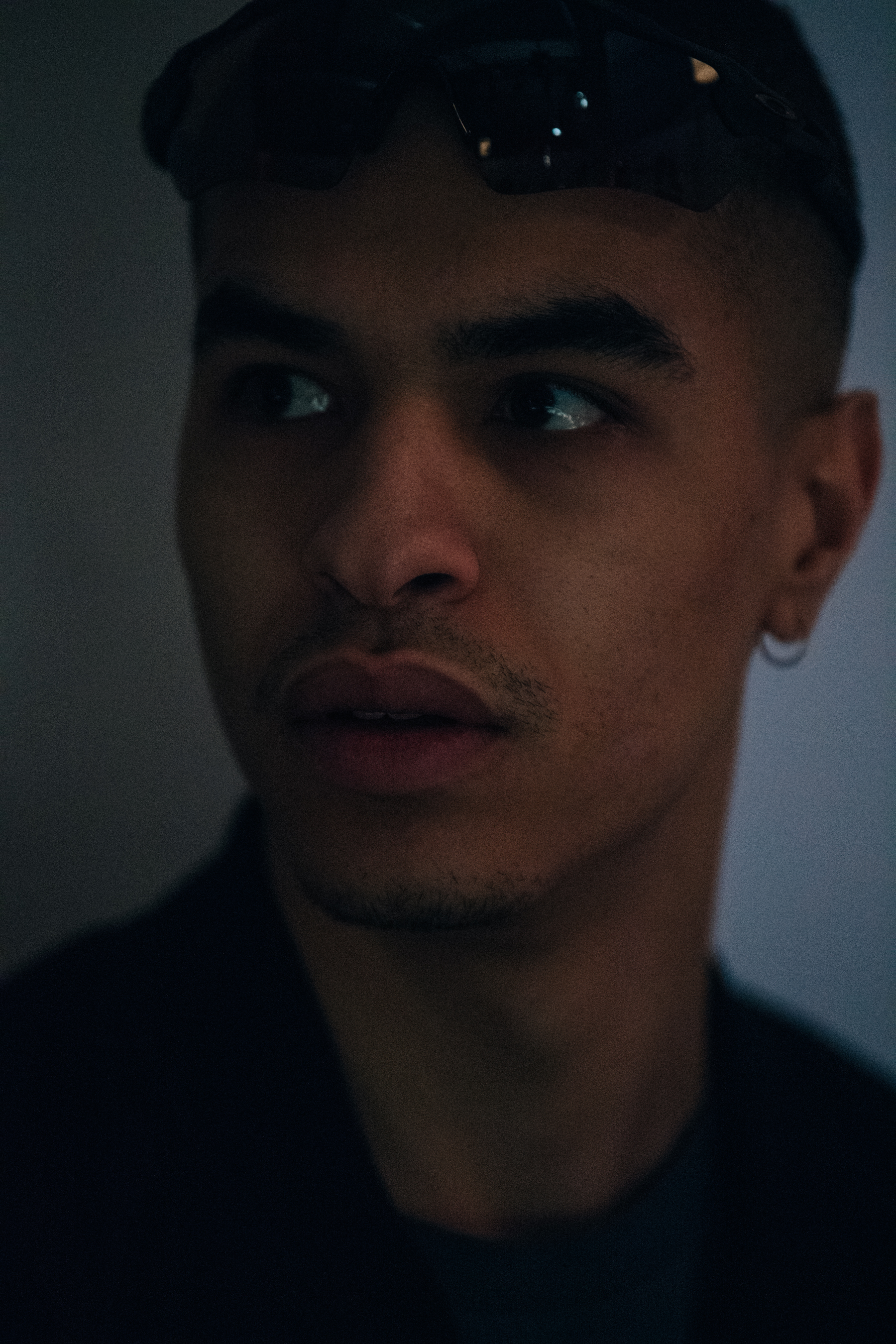 Model with shaved head wearing Oakley sunglasses