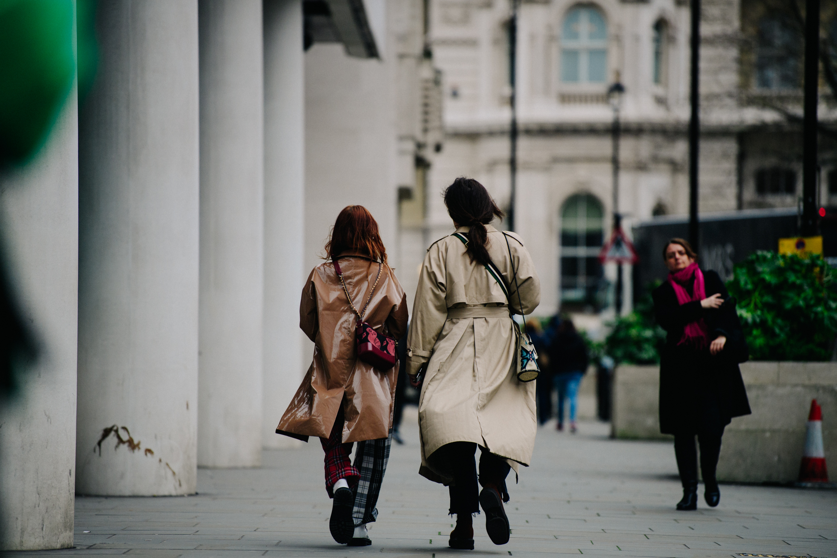 Two women wearing long tan coats