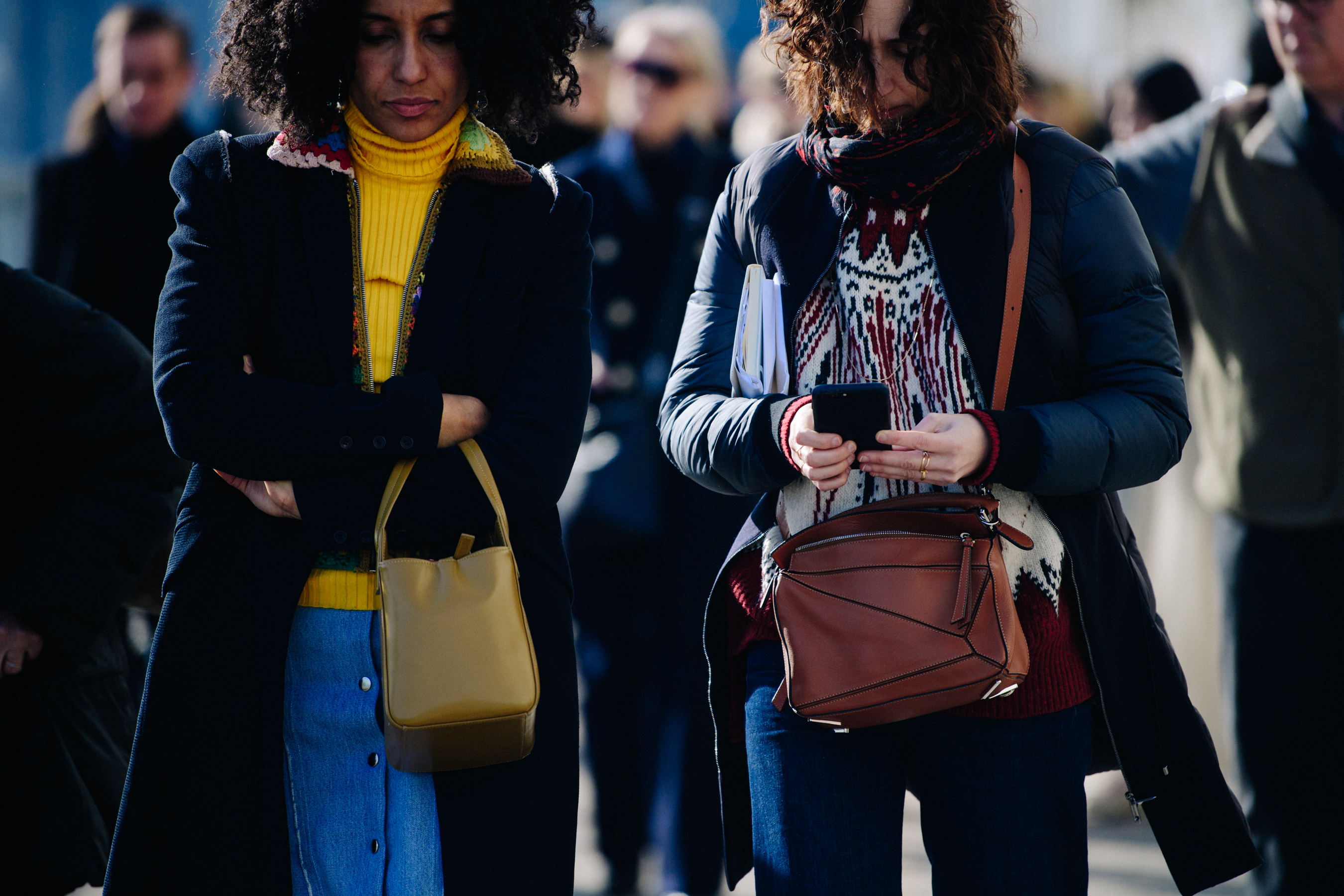 Two women wearing dark long coats