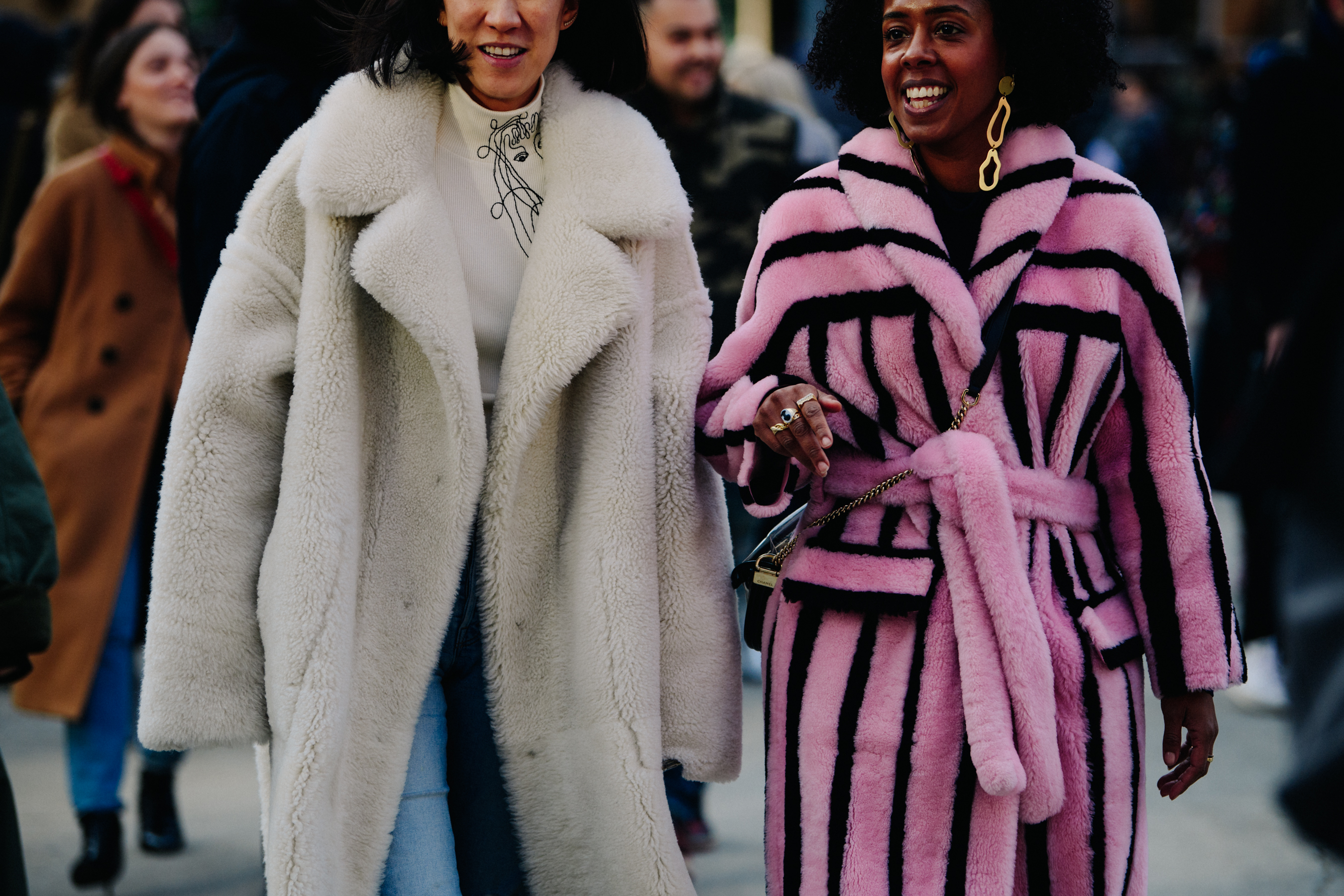 Two women wearing colourful fur coats