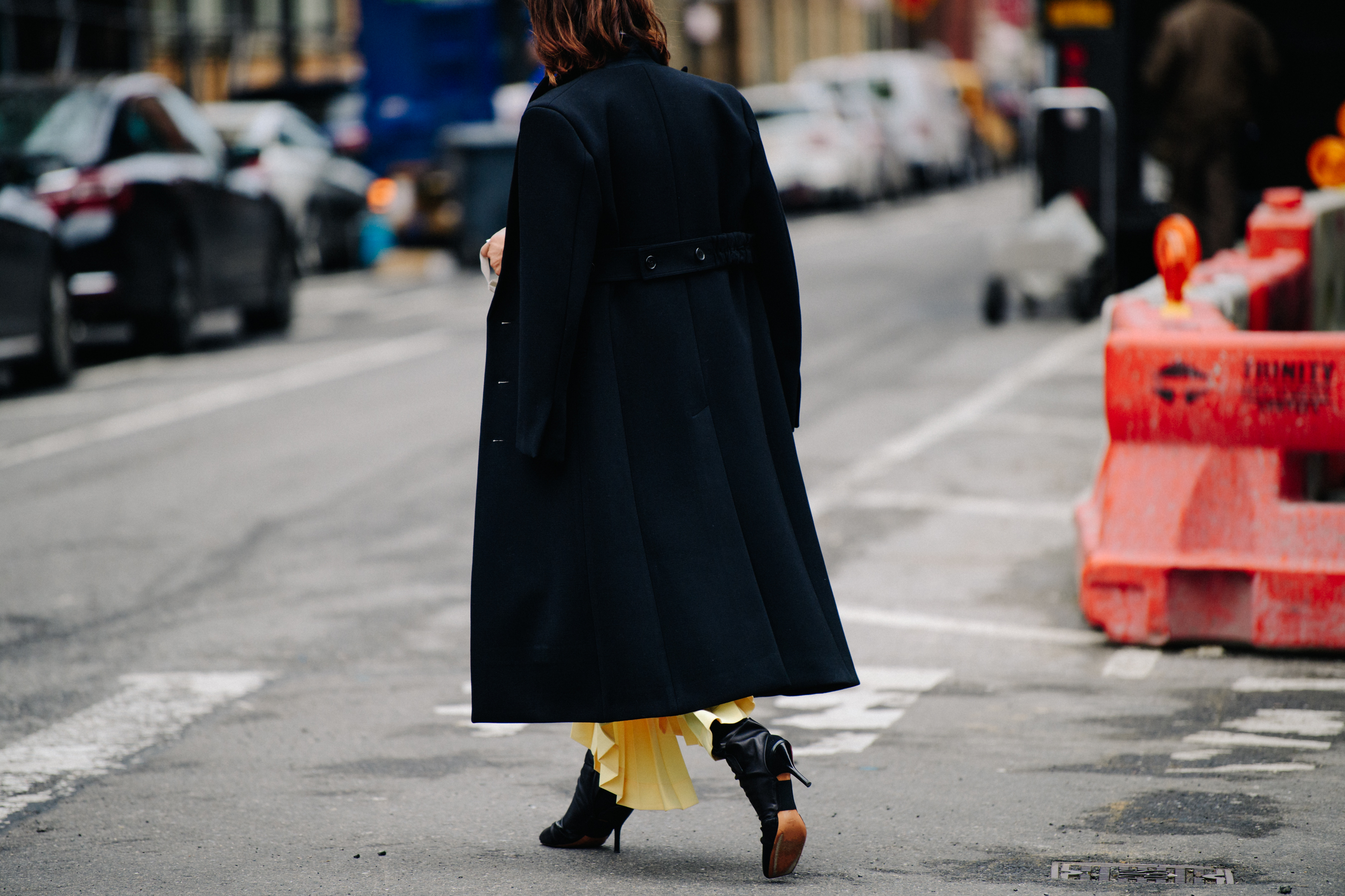 Woman wearing black coat over yellow dress