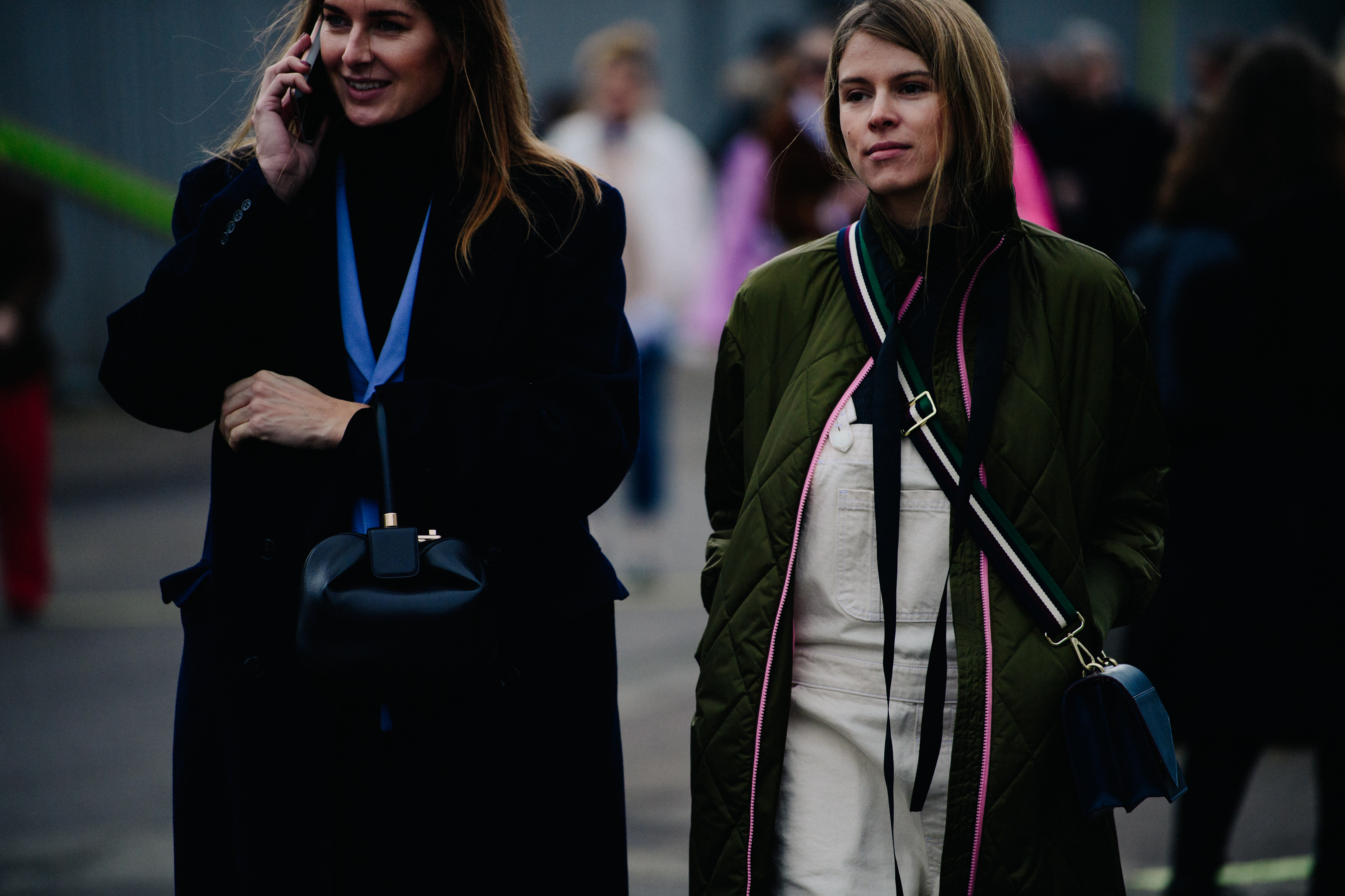 Two women holding black leather bags