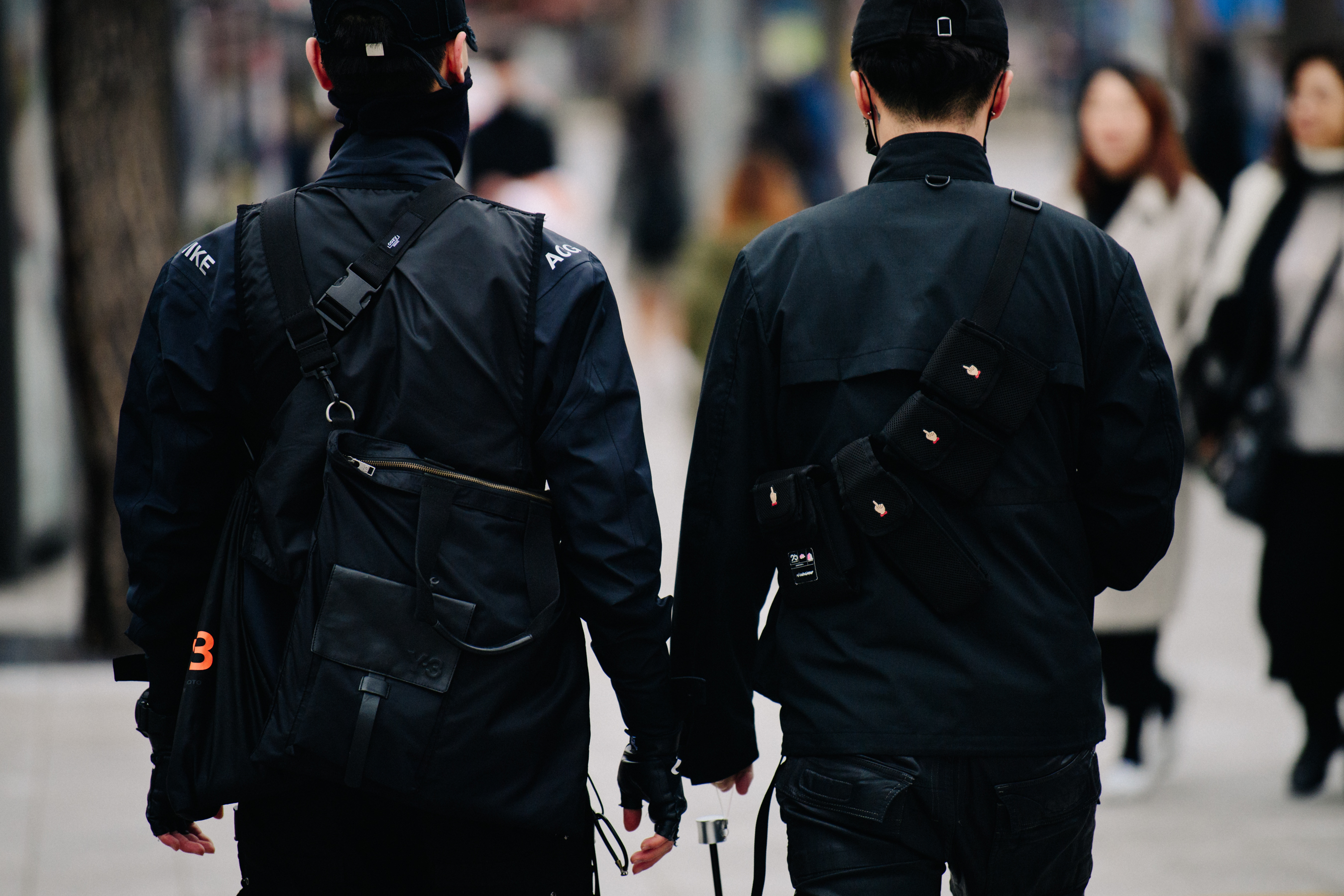 Two men wearing black jackets and bags