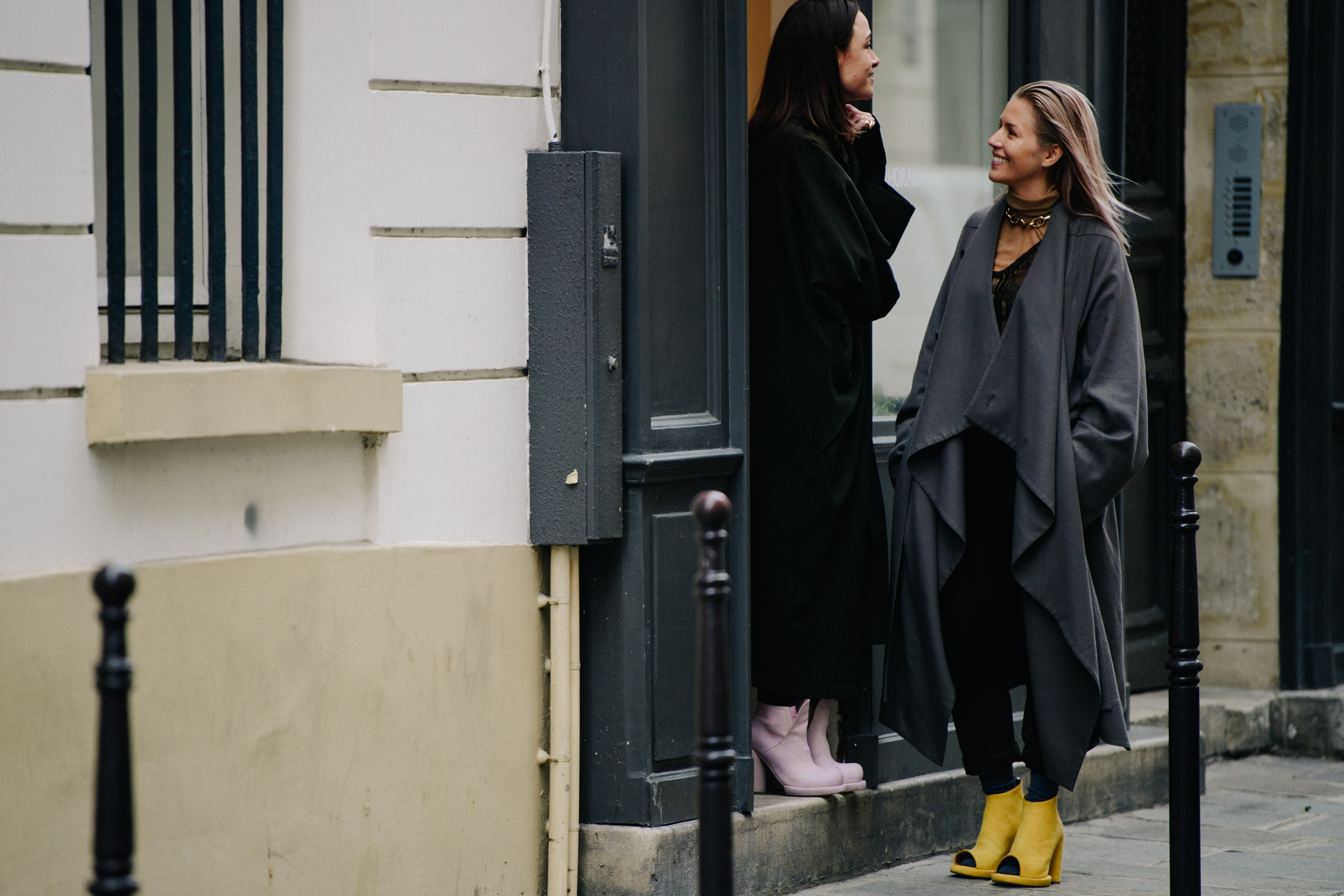 Two women wearing long grey and black coats