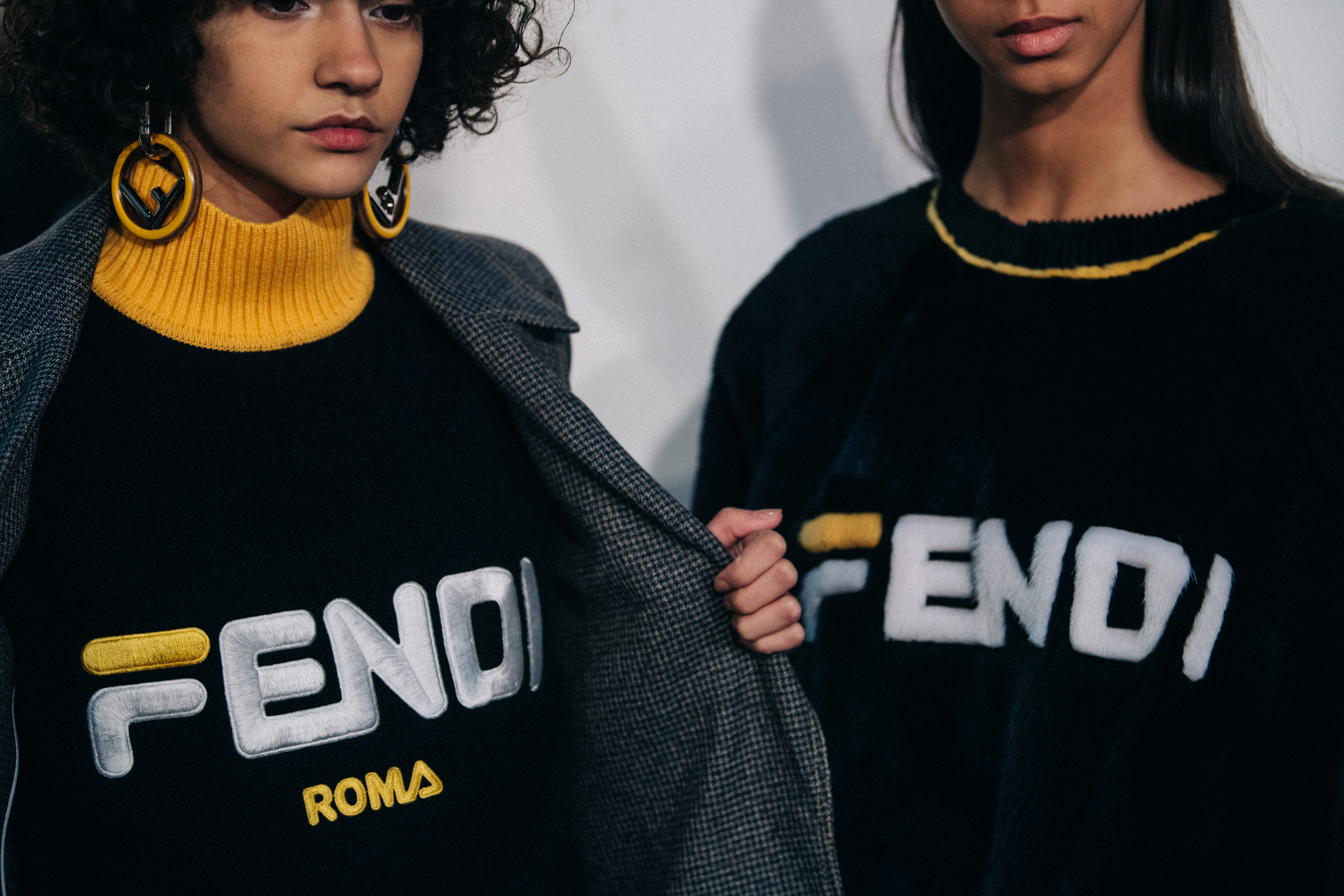 Two models wearing black Fendi jumpers