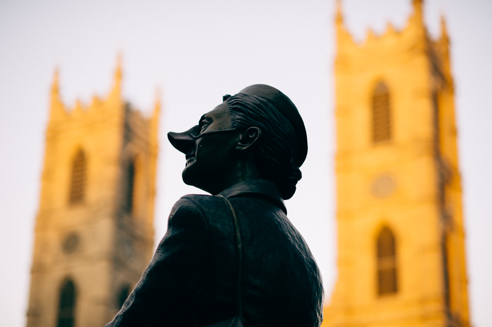 Statue of a man overlooking church in Canada