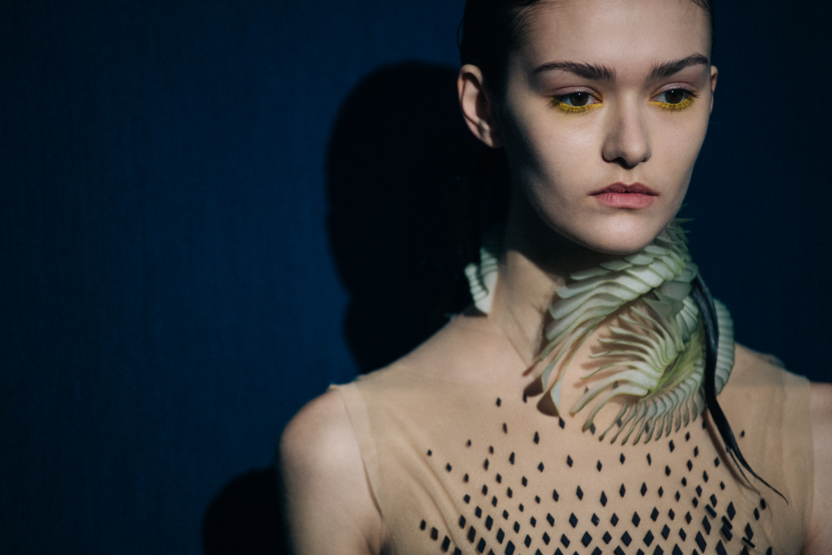 Model wearing green neck piece backstage