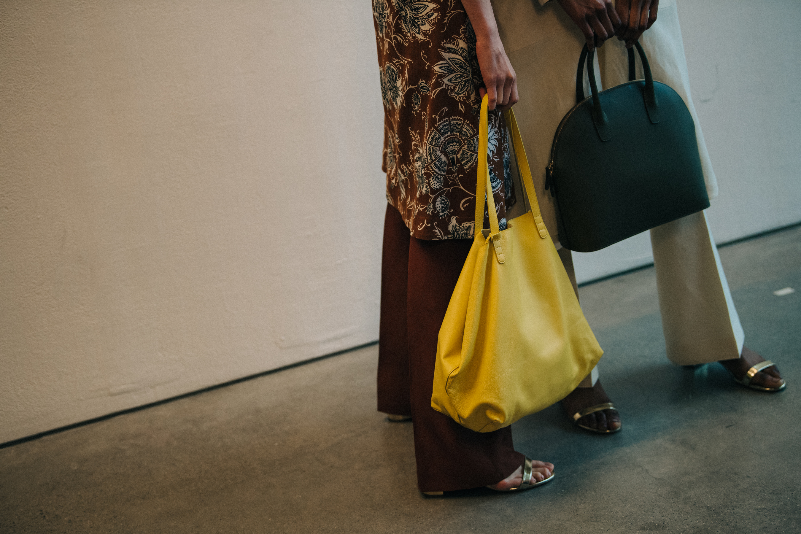 Models holding yellow and green bags
