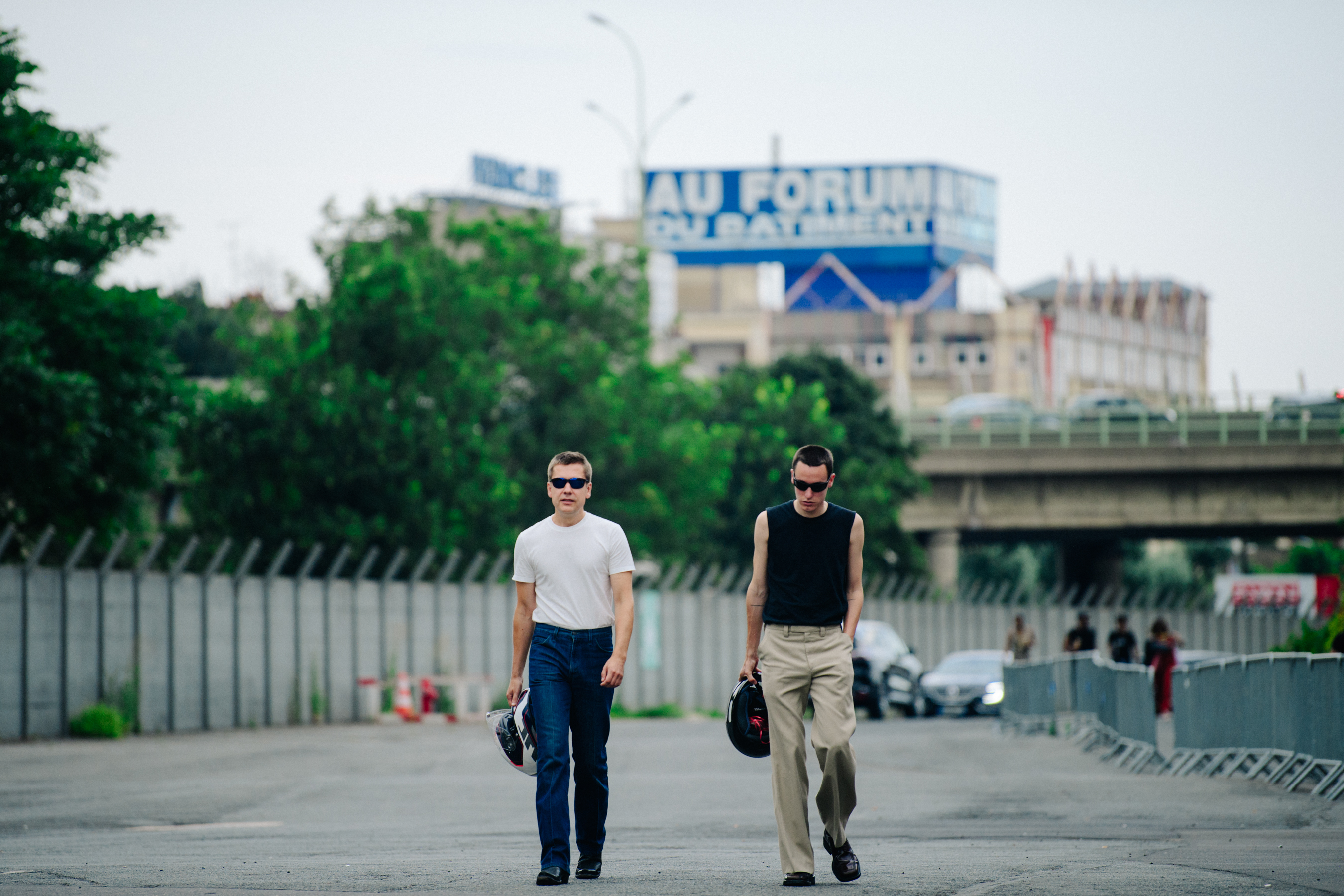 Two men carrying motorcycle helmets