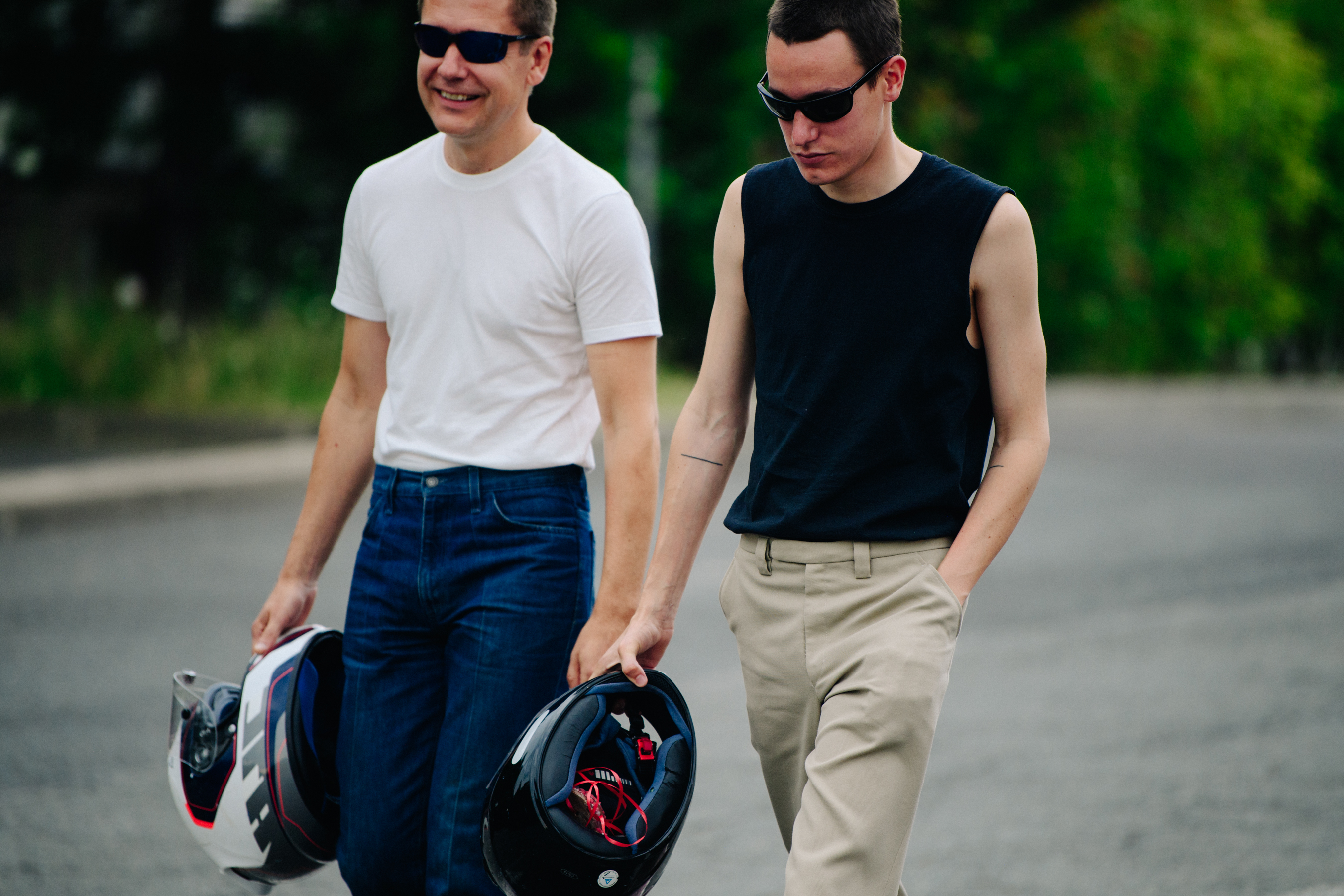 Two men carrying motorcycle helmets