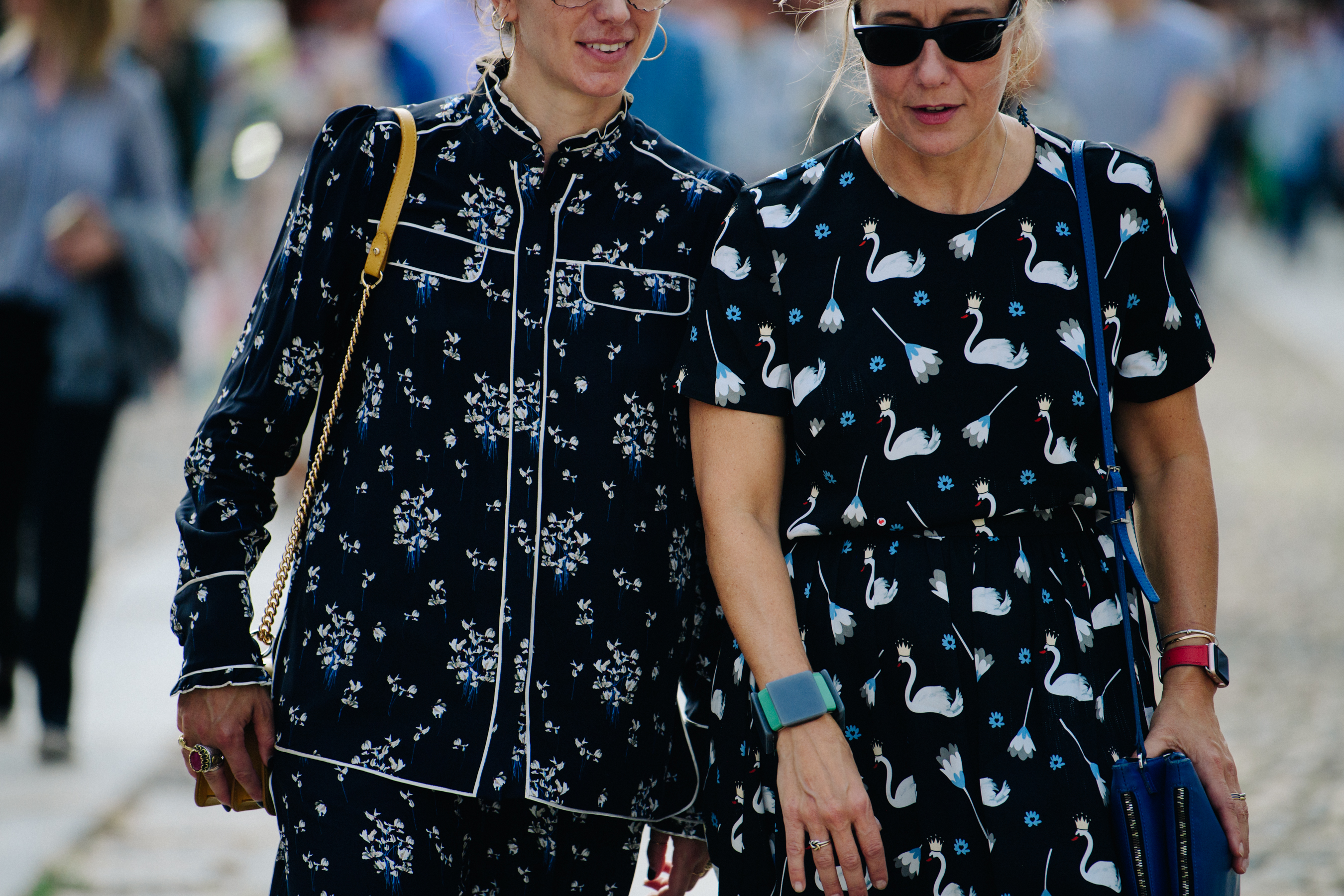 Two women wearing black floral dresses