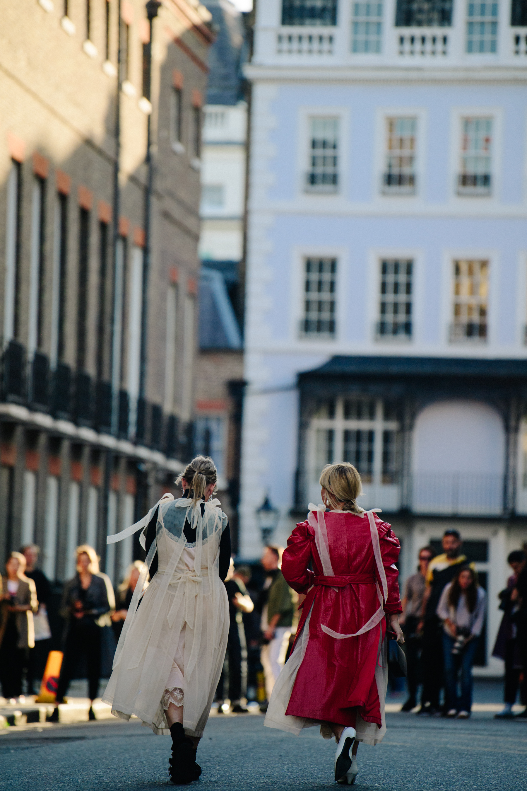 Two women wearing beige and red