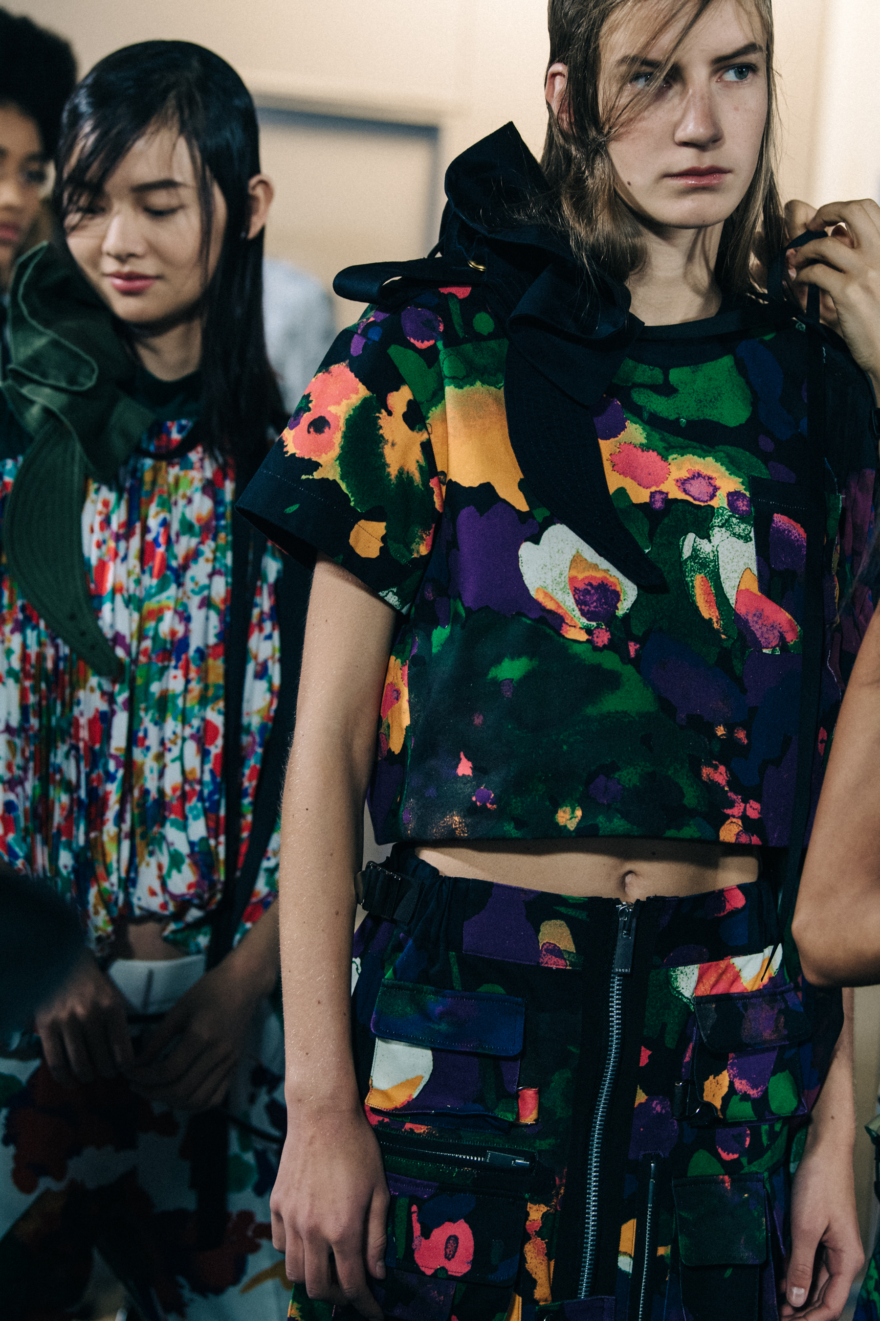 Models wearing colourful Sacai outfits backstage