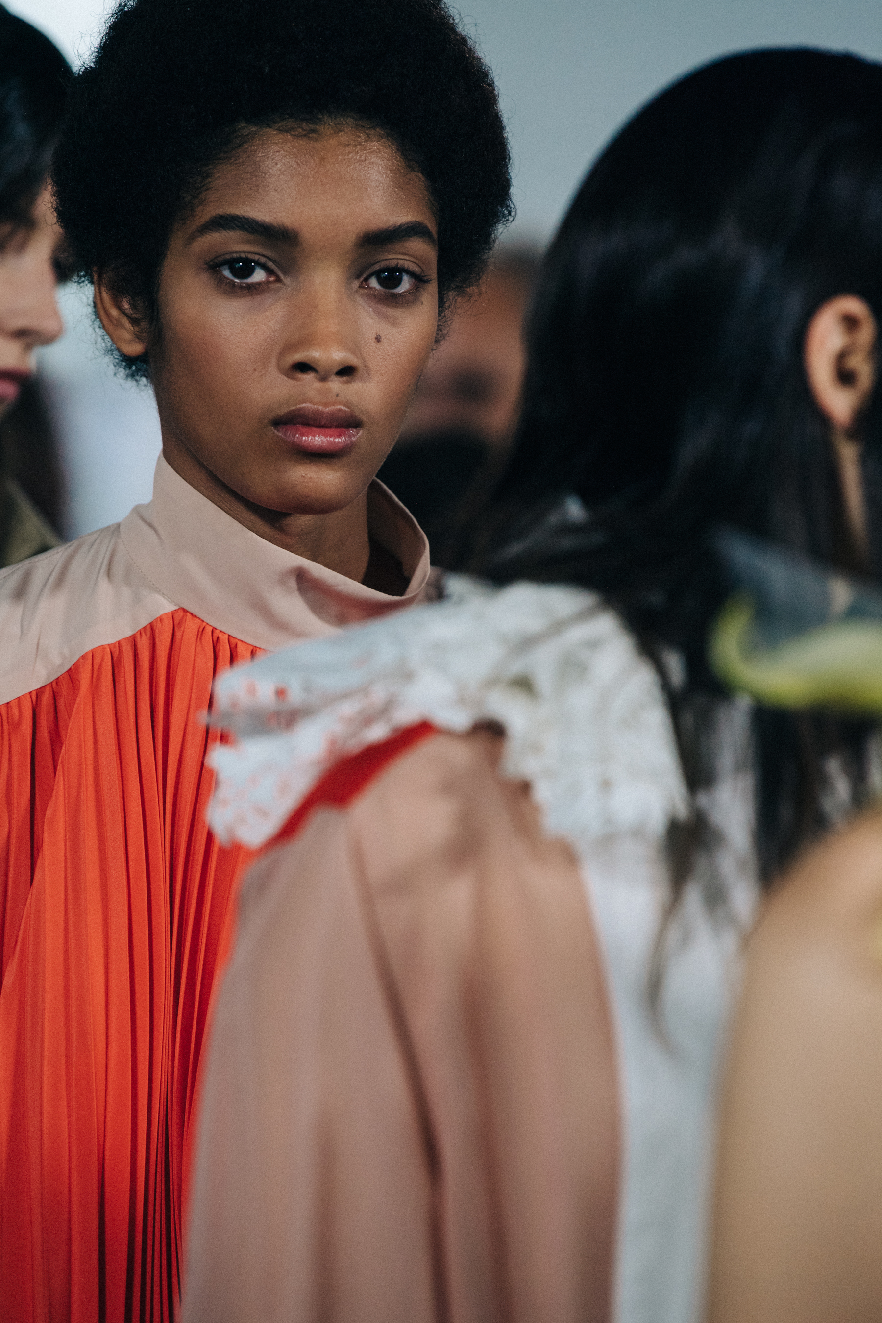 Models wearing colourful Sacai outfits backstage