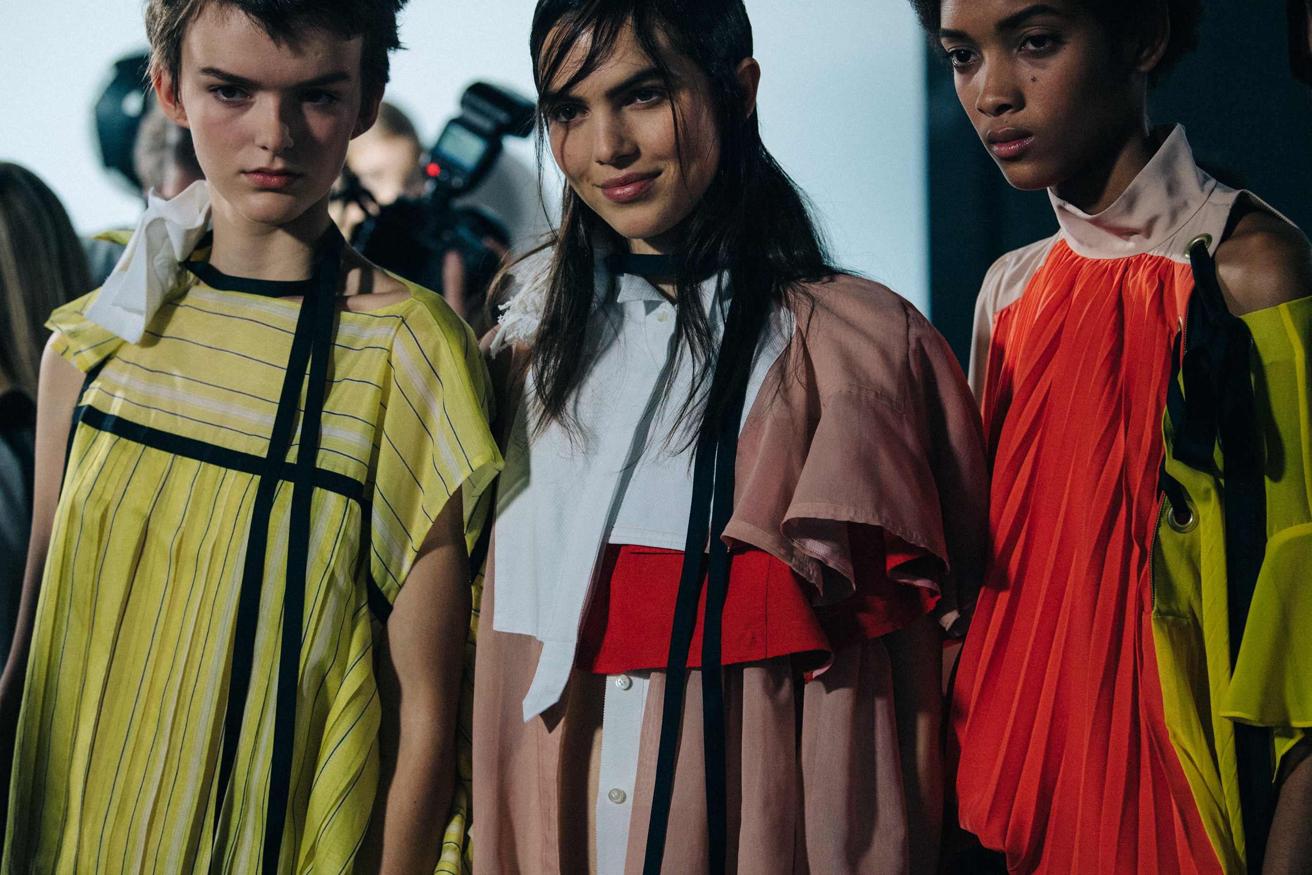 Models wearing colourful Sacai outfits backstage