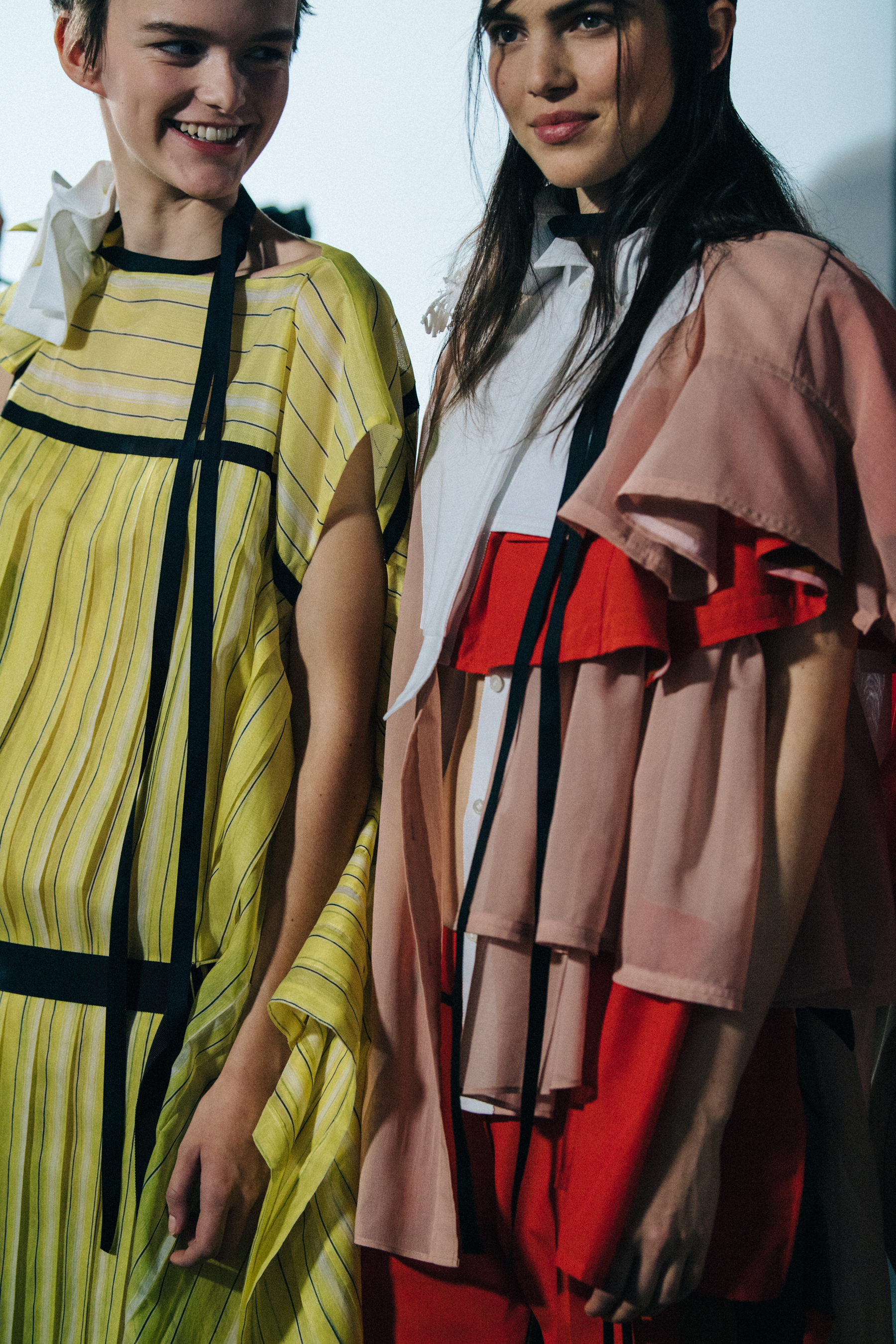 Models wearing colourful Sacai outfits backstage