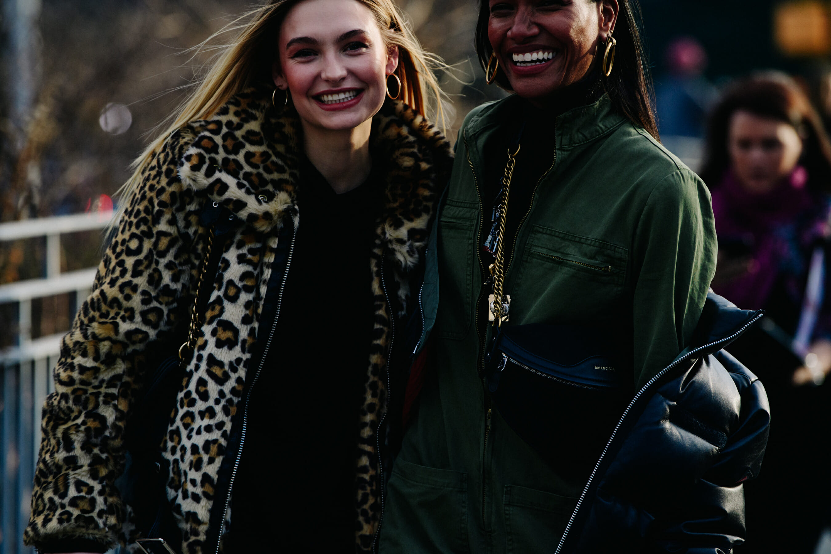 Two women wearing light coats