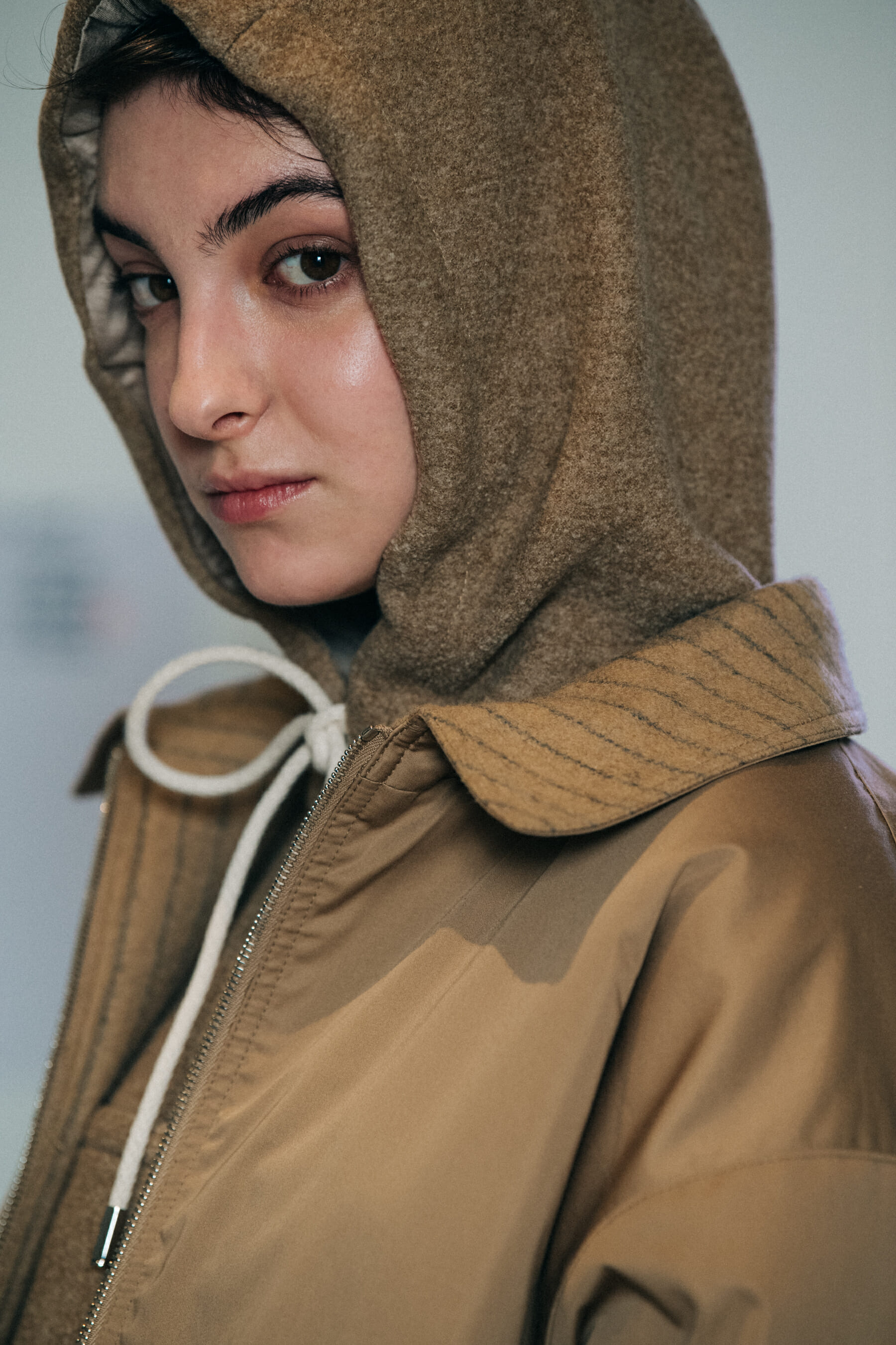 Model wearing tan hood backstage at Nehera