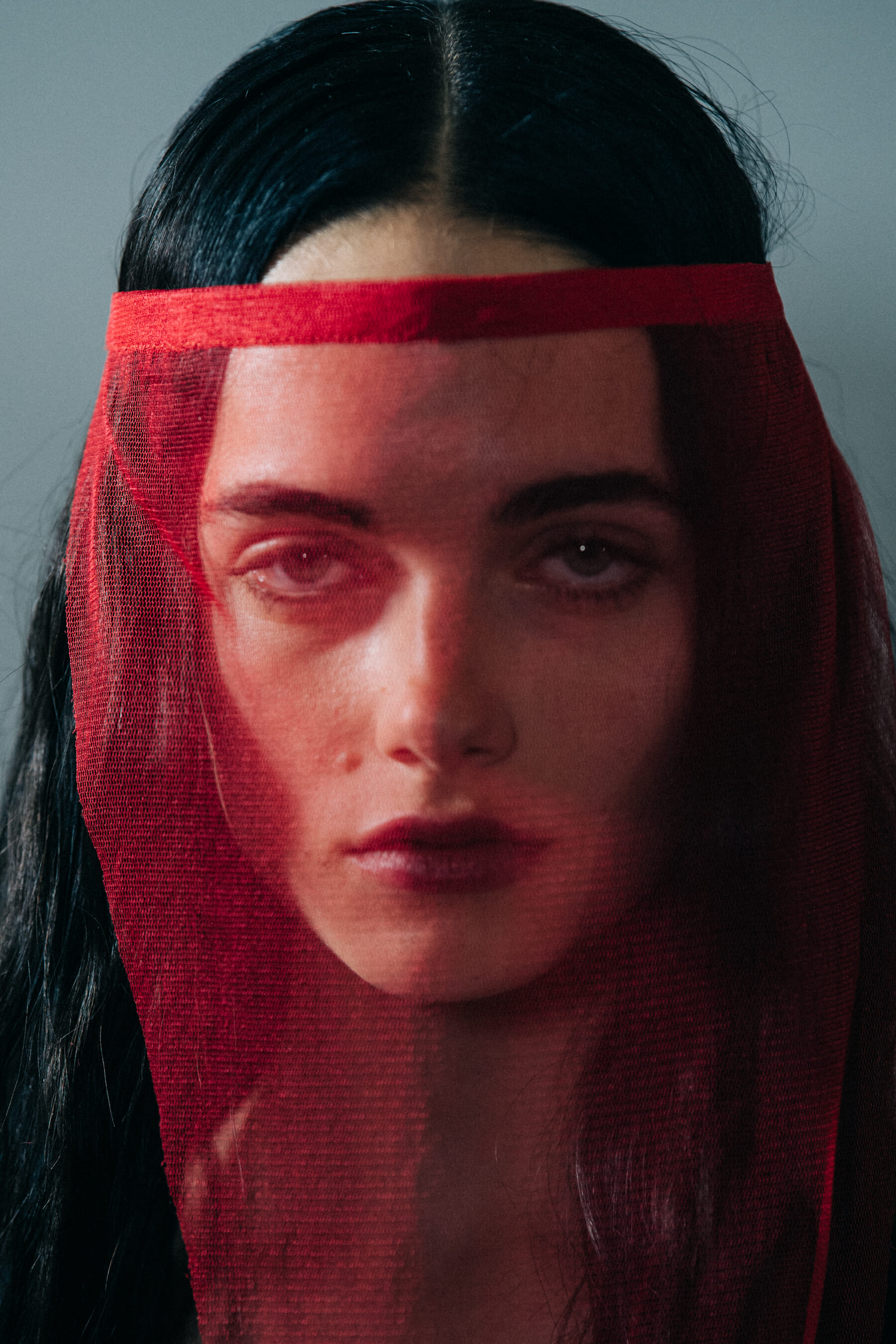 Portrait of model wearing red veil at Ann Demeulemeester
