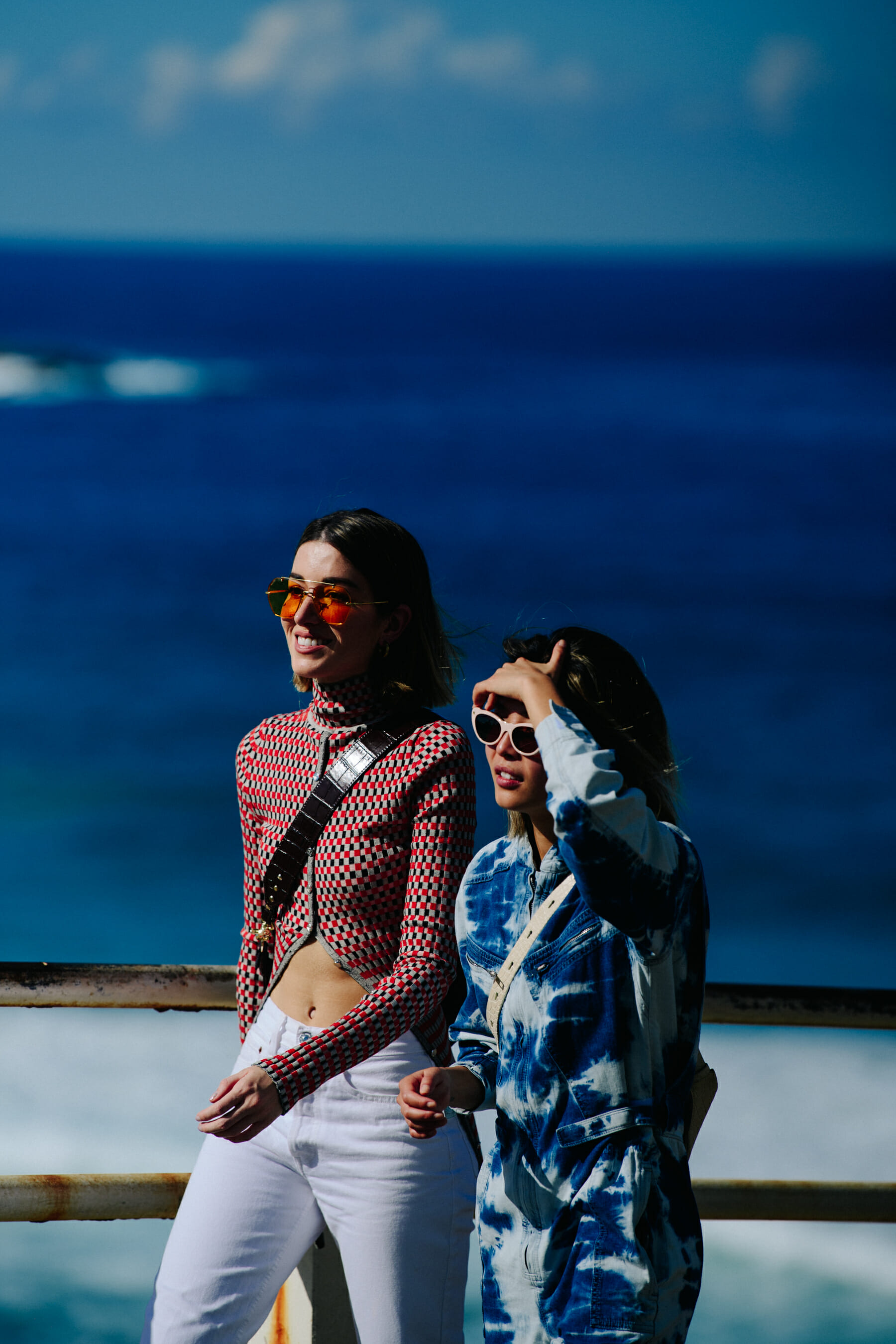 Two women wearing colourful sunglasses